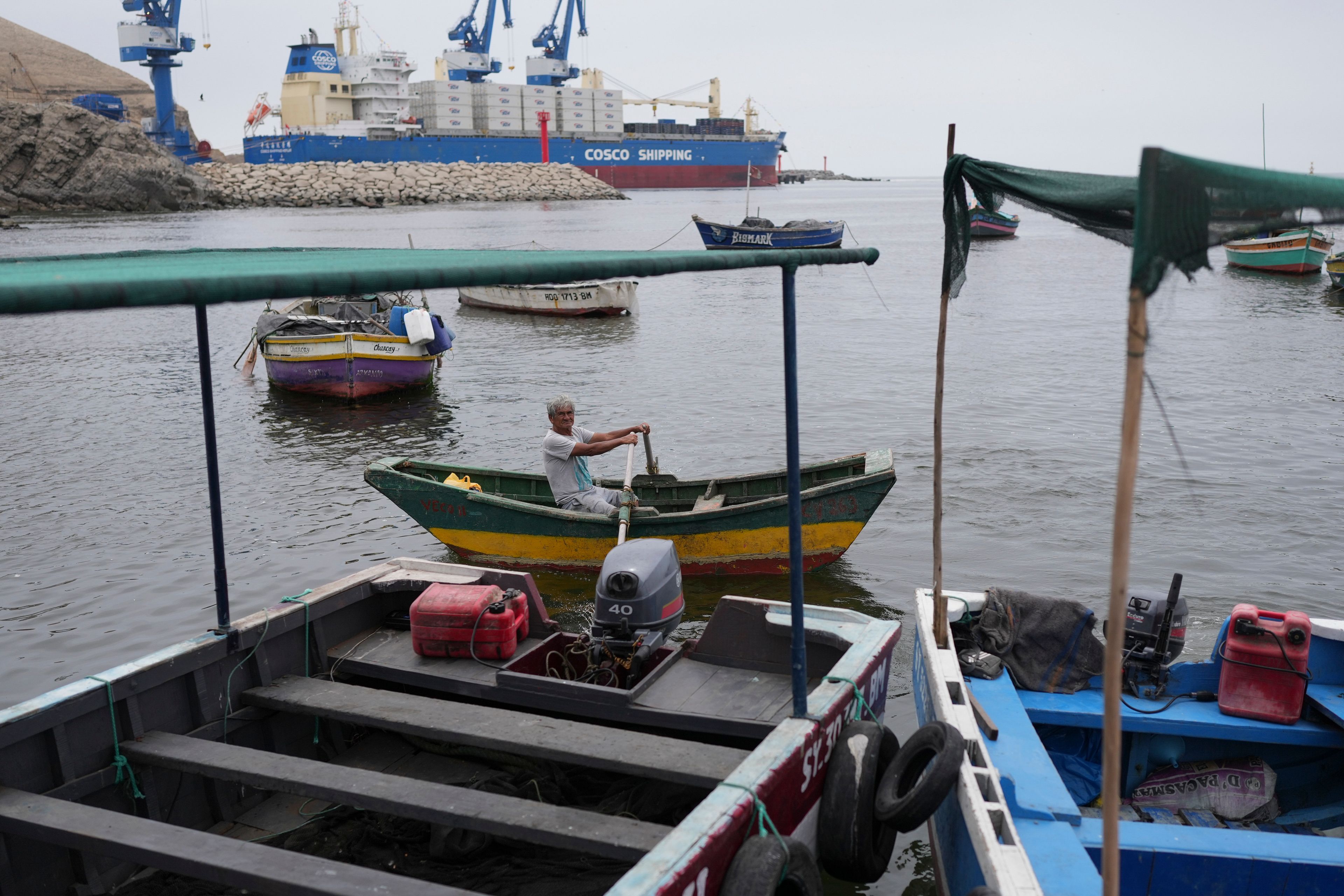 A fisherman travels on a boat near a Chinese-funded port construction in Chancay, Peru, Tuesday, Nov. 12, 2024. (AP Photo/Silvia Izquierdo)