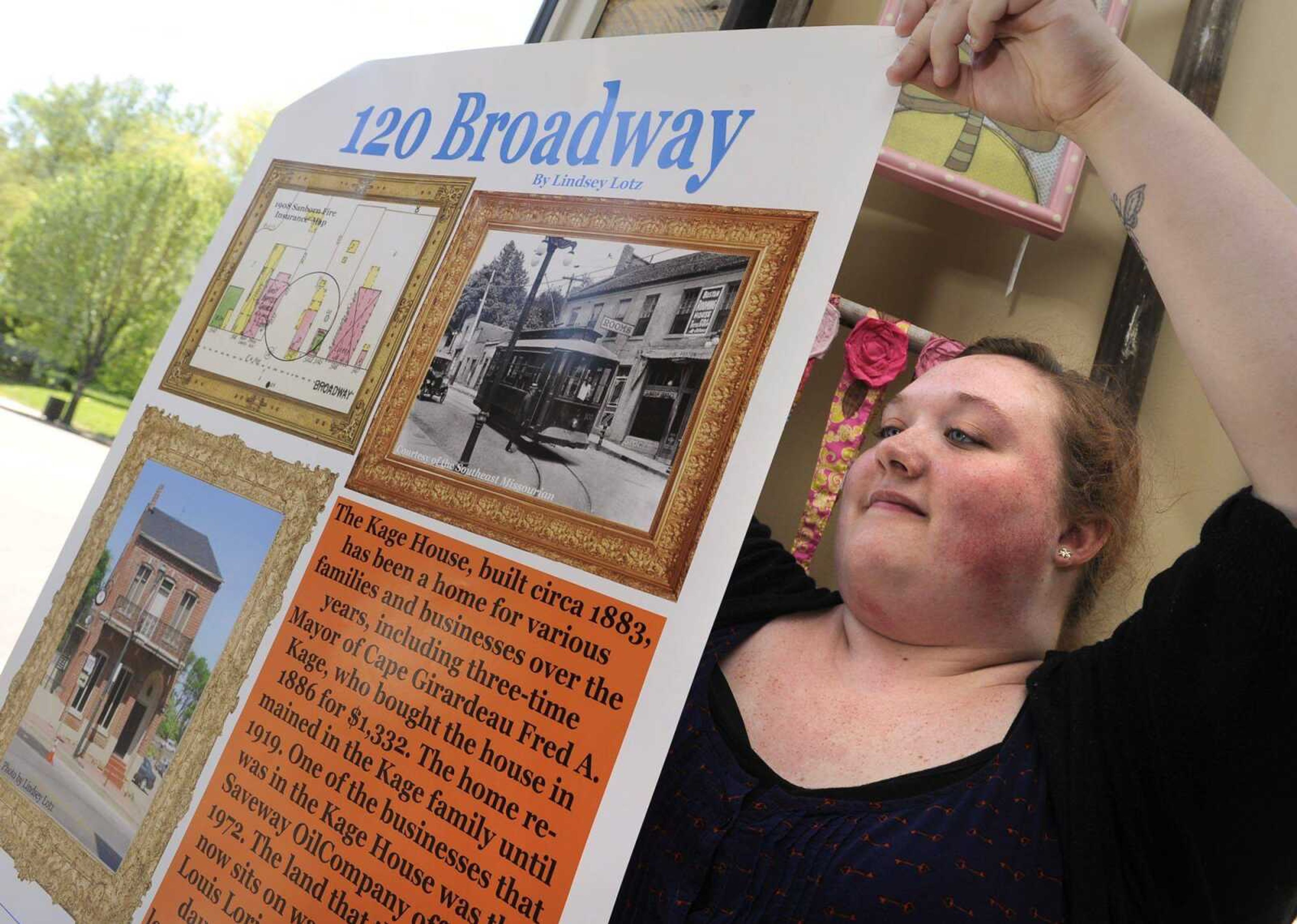 Lindsey Lotz, a senior in historic preservation at Southeast Missouri State University, places a poster in the window of Sweet Designs Boutique, 120 Broadway, on Friday in downtown Cape Girardeau. The poster and others detail the history of several downtown buildings. (Fred Lynch)