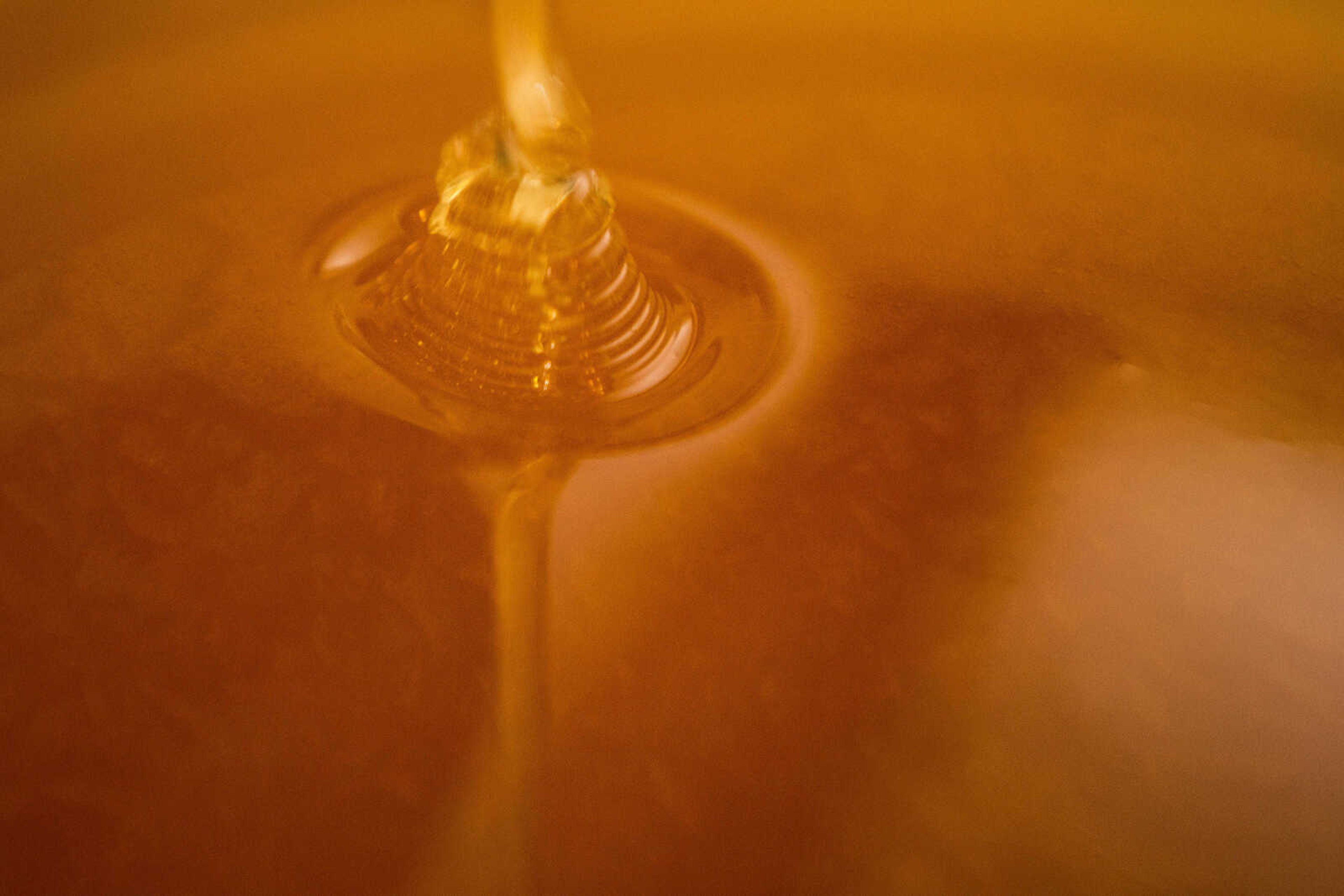 Honey flows from one straining tank to another at Paul Koeper's home in Jackson.