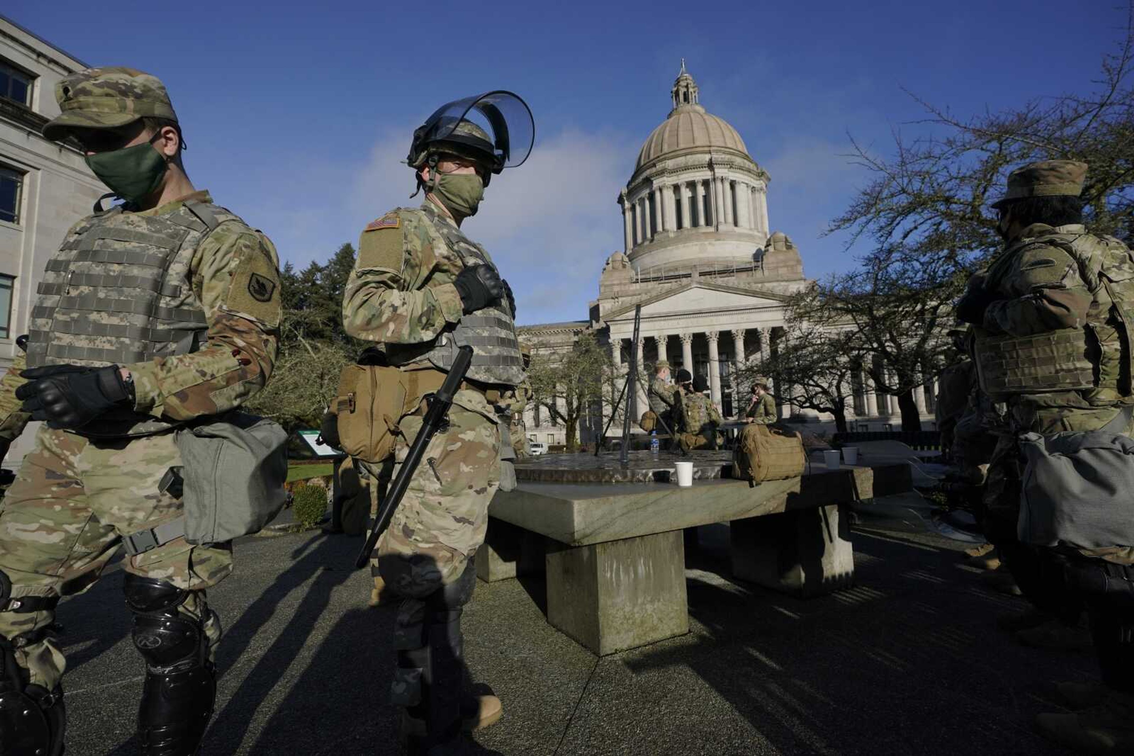 Members of the Washington National Guard stand at a sundial near the Legislative Building at the Capitol in Olympia, Washington. Governors in some states have called out the National Guard, declared states of emergency and closed their capitols over concerns about potentially violent protests.