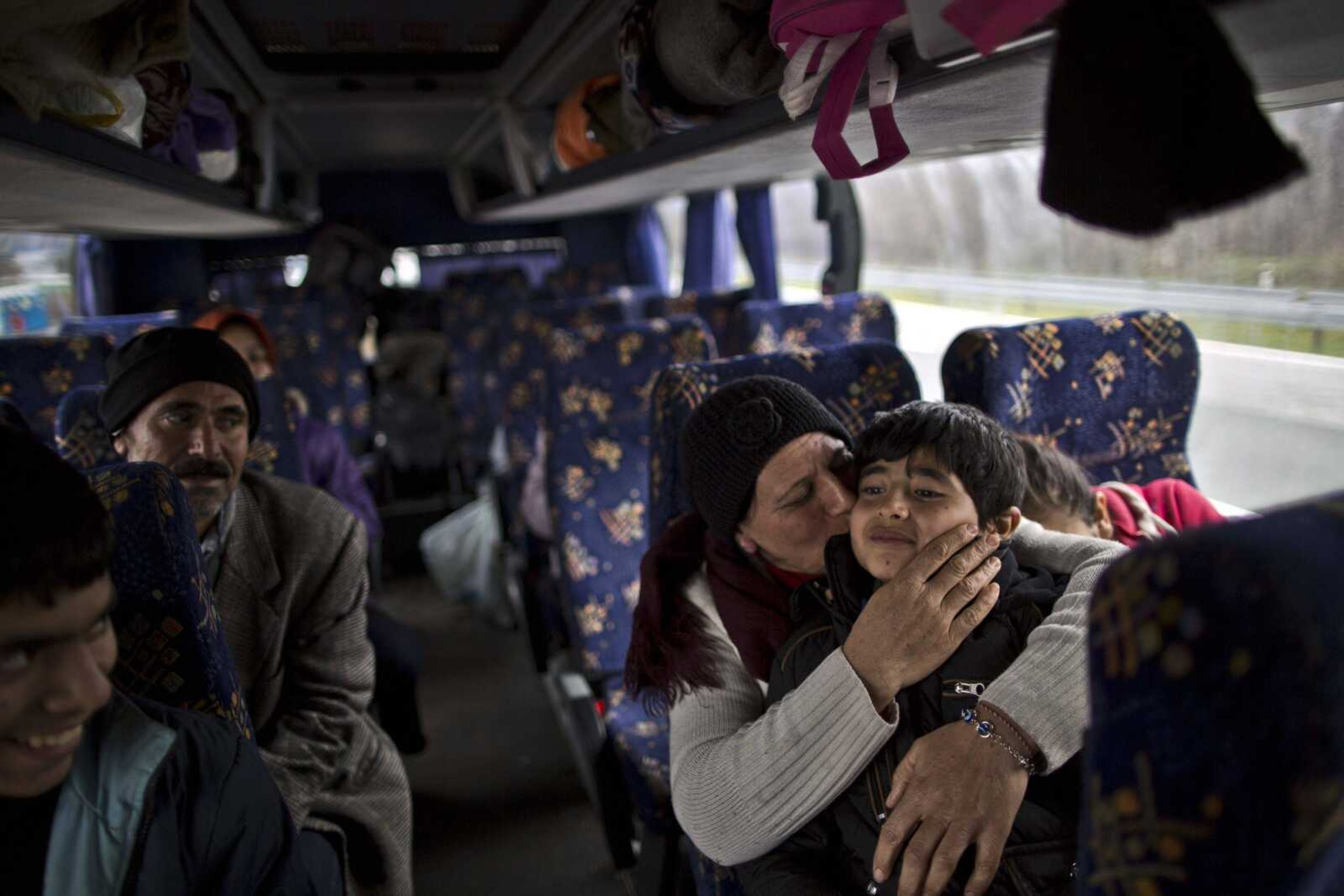 Bessi Qasim, 42, a Yazidi refugee from Sinjar, Iraq, kisses her son Dildar, 10, as she and her family rest in a bus Dec. 6, waiting to be transported to the train station where Serbian authorities load trains with refugees to Croatia. (Muhammed Muheisen ~ Associated Press)