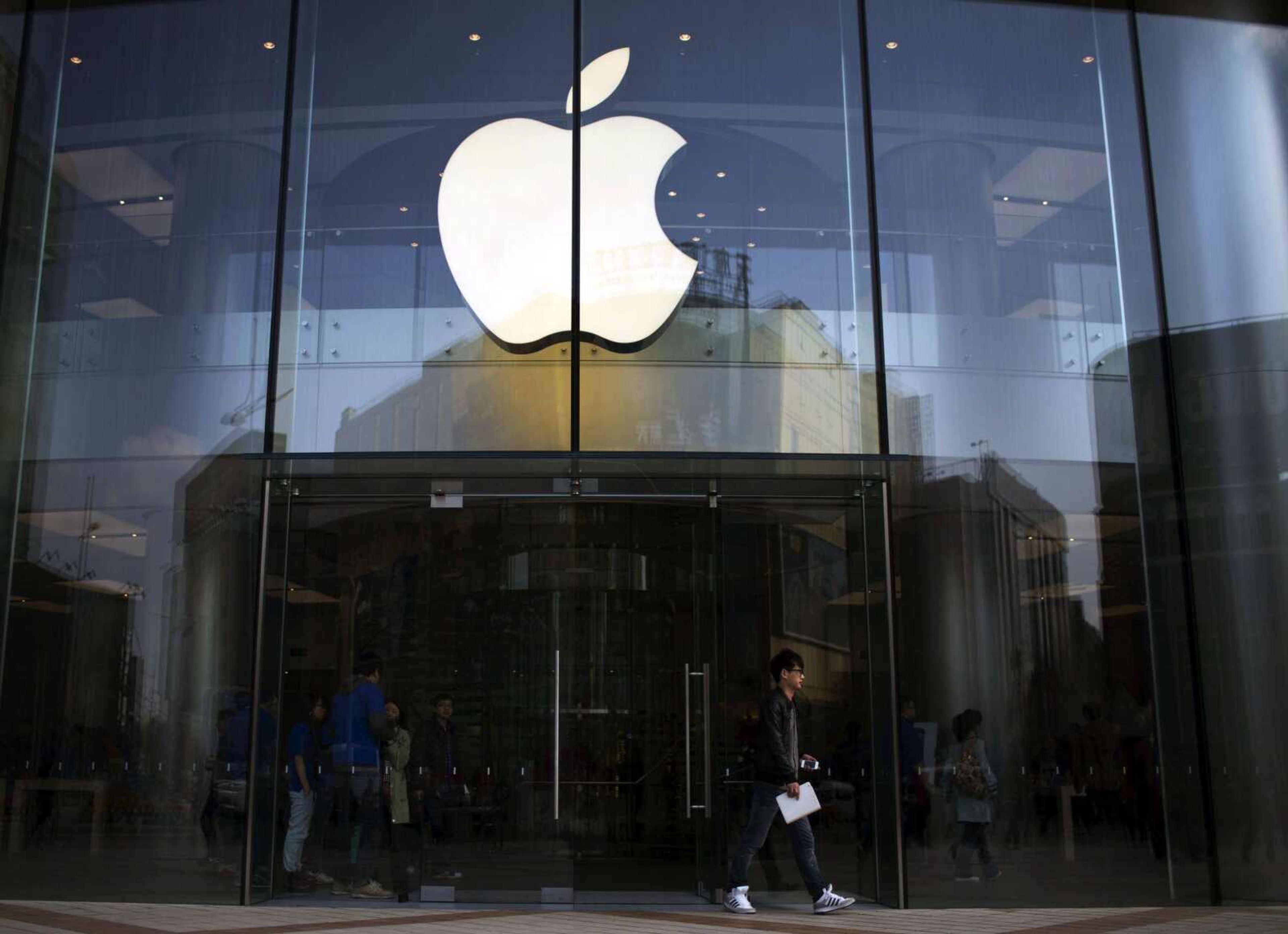 In this Monday April 1, 2013 photo, a man leaves an Apple store with an iPhone and an iPad in his hands in central Beijing, China. Apple Inc., the maker of the iPhone and iPad, reports quarterly financial results after the market closes on Tuesday. April 23, 2013. (AP Photo/Alexander F. Yuan)