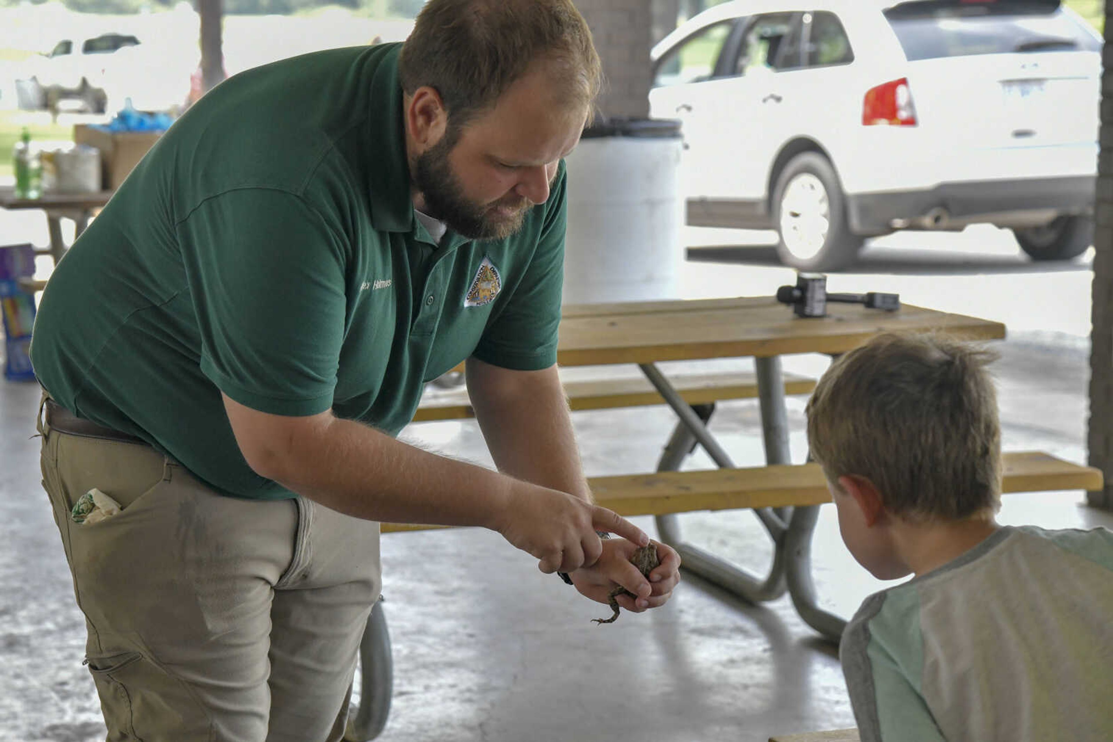 Naturalist for the Missouri Department of Conservation Alex Holmes shows an audience member the back of a toad where its venom glands are located during the EPIC Fun event at Arena Park in Cape Girardeau on Friday, July 23, 2021.