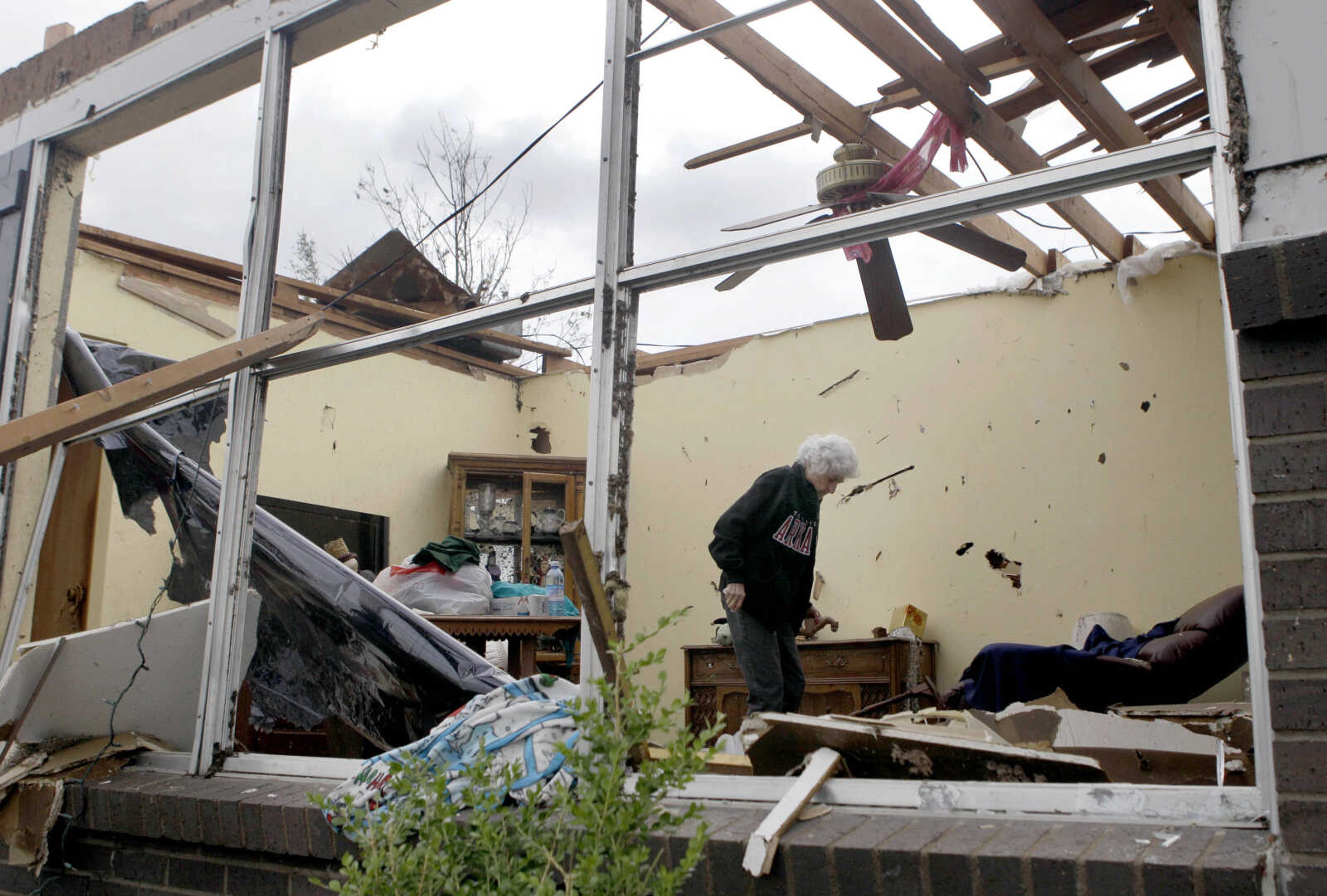 Florene Renfro is seen through a window as she searches through her tornado-damaged house Wednesday, May 25, 2011, in Joplin , Mo. Renfro, 85, has decided she will abandon the home she's lived in since 1967 and move in with her daughter in Arkansas after a massive tornado hit Joplin on Sunday night. (AP Photo/Jeff Roberson)