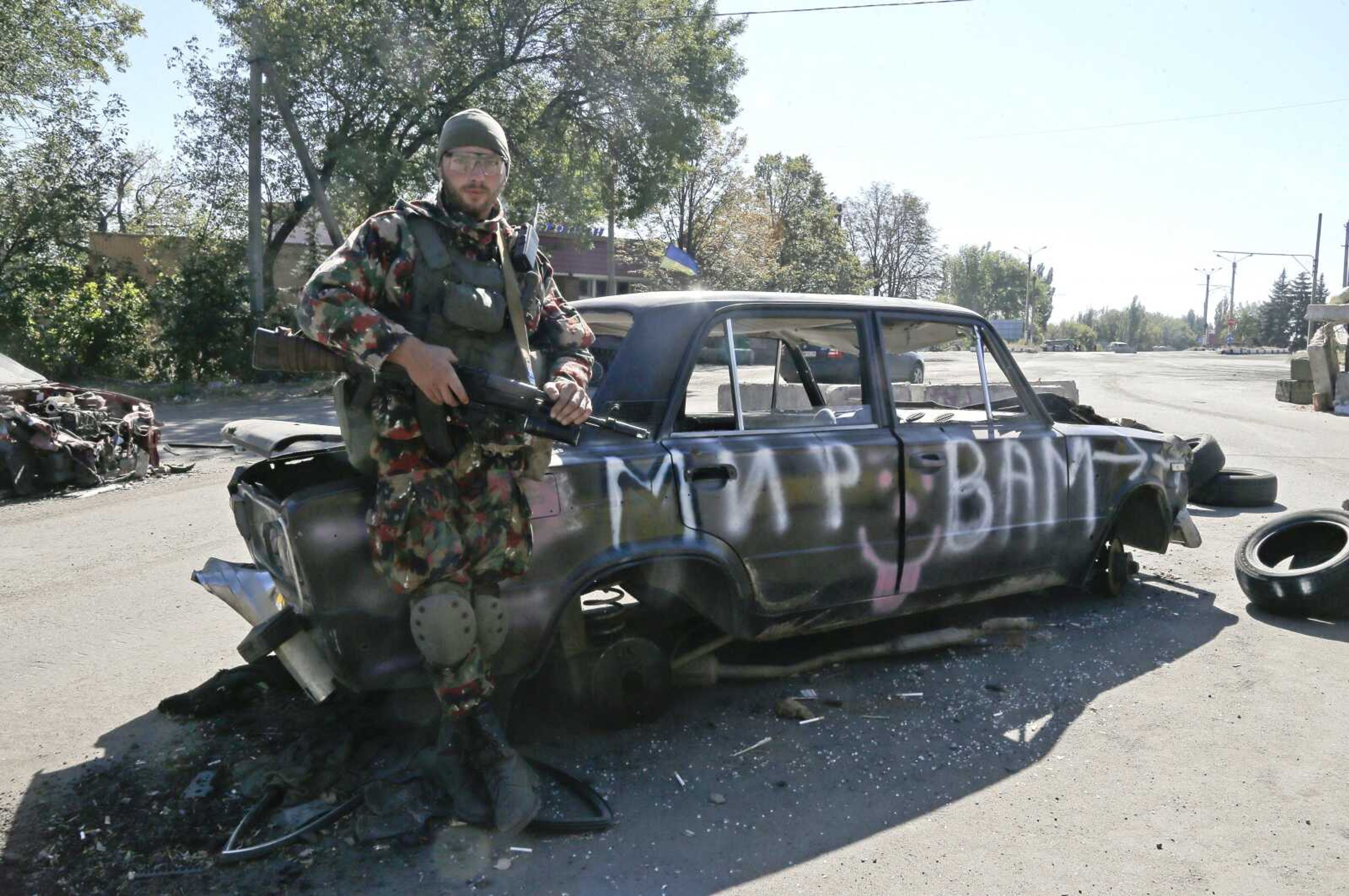 A Ukrainian army soldier controls a road Thursday at the check point in Debaltsevo, Donetsk&#8217;s region in Ukraine. The inscription on the burned car is &#8220;Peace for you.&#8221;<br>Efrrem Lukatsky<br>Associated Press