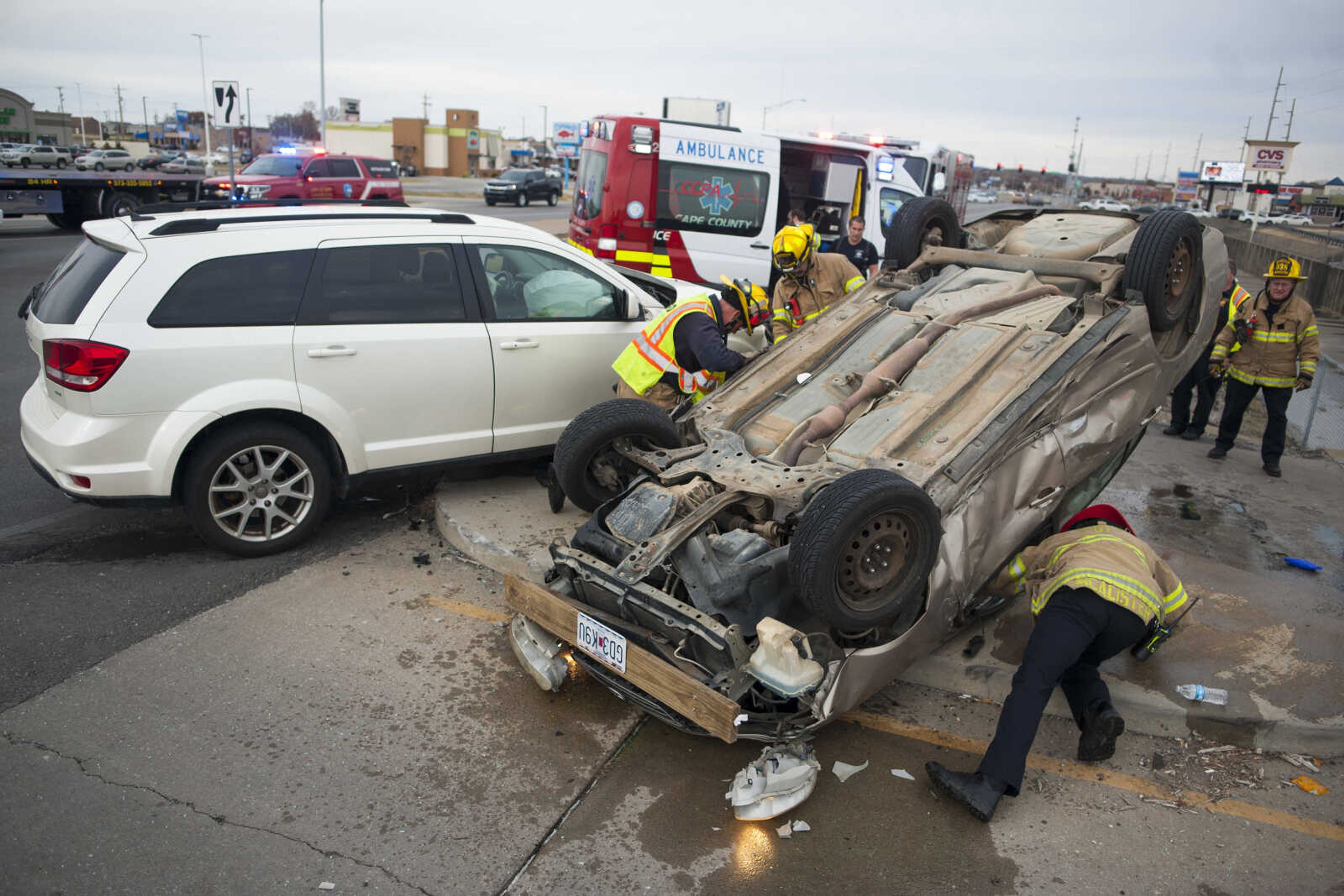 Members of the Cape Girardeau Fire Department inspect an overturned vehicle Monday, Nov. 18, 2019, at the scene of a three-vehicle collision at the intersection of South Kingshighway and Good Hope Street in Cape Girardeau.