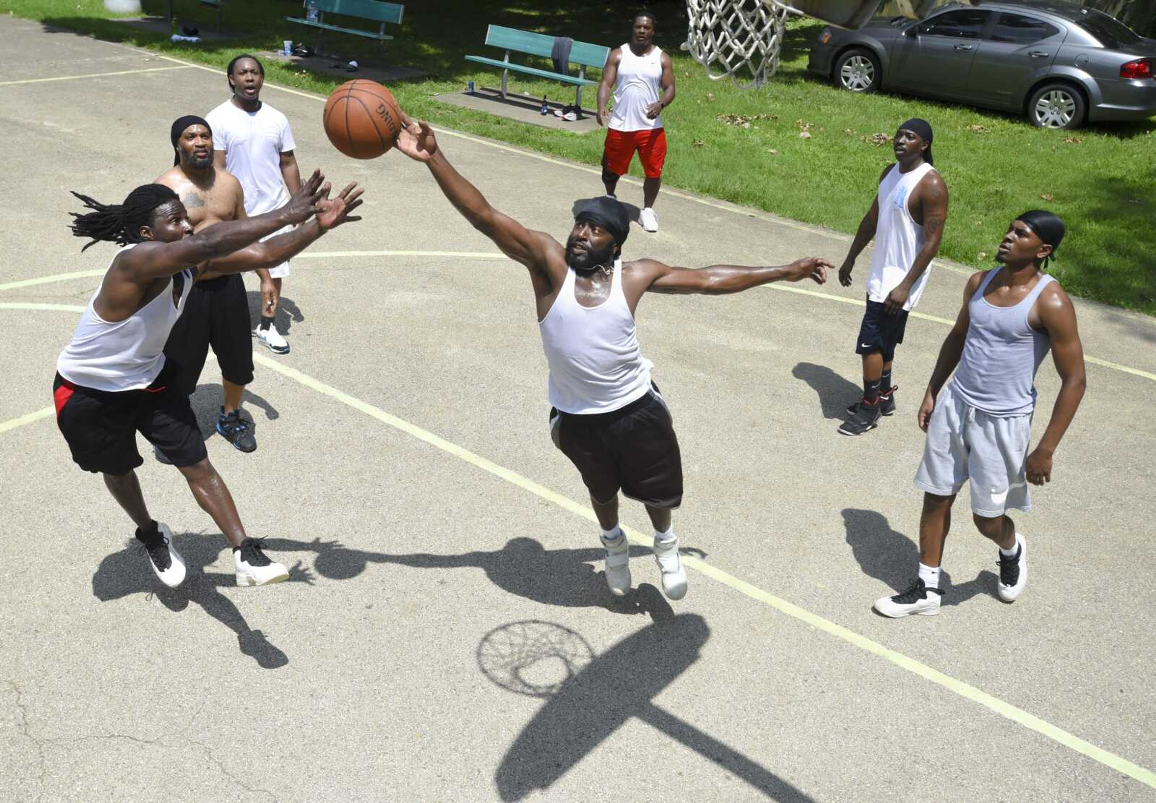 Allen Mills, center, tips a rebound out of the hands of Jay Fields, far left, during a weekly pick-up basketball game July 21 at Indian Park in Cape Girardeau.