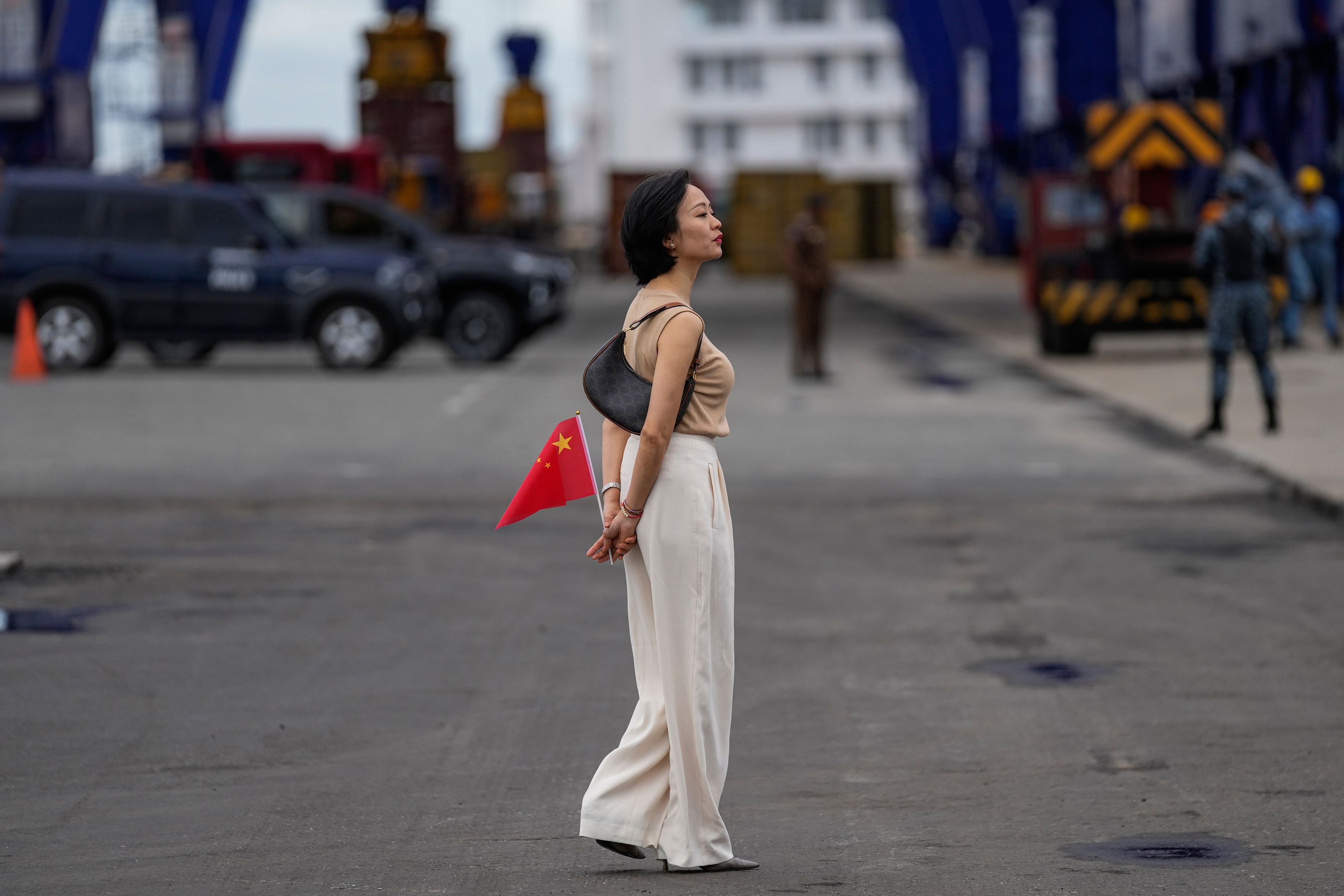 A Chinese national residing in Sri Lanka holds a national flag as she waits to welcome the Chinese navy's sail training warship Po Lang at a port in Colombo, Sri Lanka, Tuesday, Oct. 8, 2024. (AP Photo/Eranga Jayawardena)