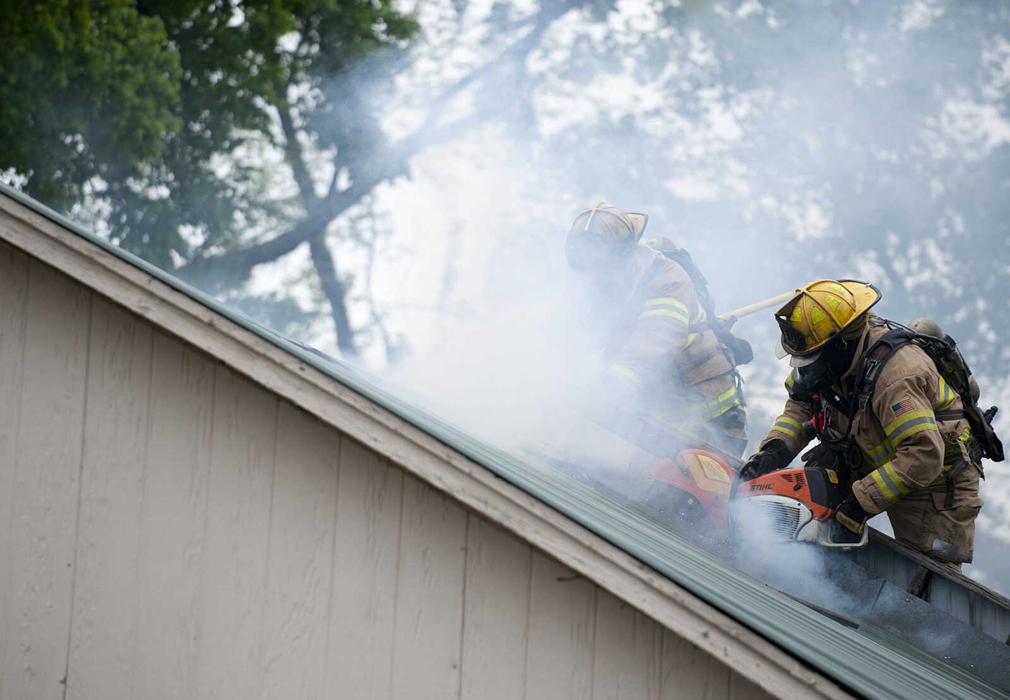 Cape Girardeau firefighters use a saw to cut through the roof as they battle a structure fire at 710 Morgan Oak  St., Tuesday, April 29, in Cape Girardeau. A Cape Girardeau Police officer saw the fire and called it in at 1:16 p.m. The building contained two apartments that were home to five people, though no one was home at the time of the fire. The cause of the fire is under investigation.