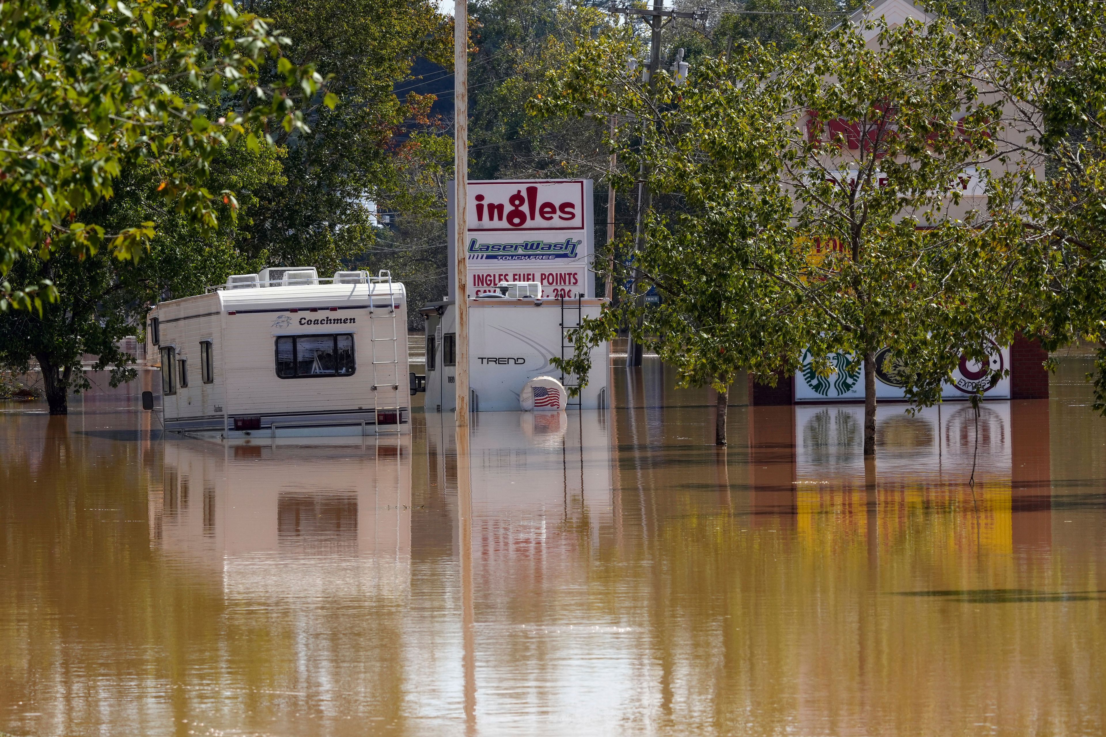 A couple of RVs are abandoned in the flooded Ingles parking lot due to the torrential rains from Hurricane Helene, Saturday, Sept. 28, 2024, in Morganton, N.C. (AP Photo/Kathy Kmonicek)