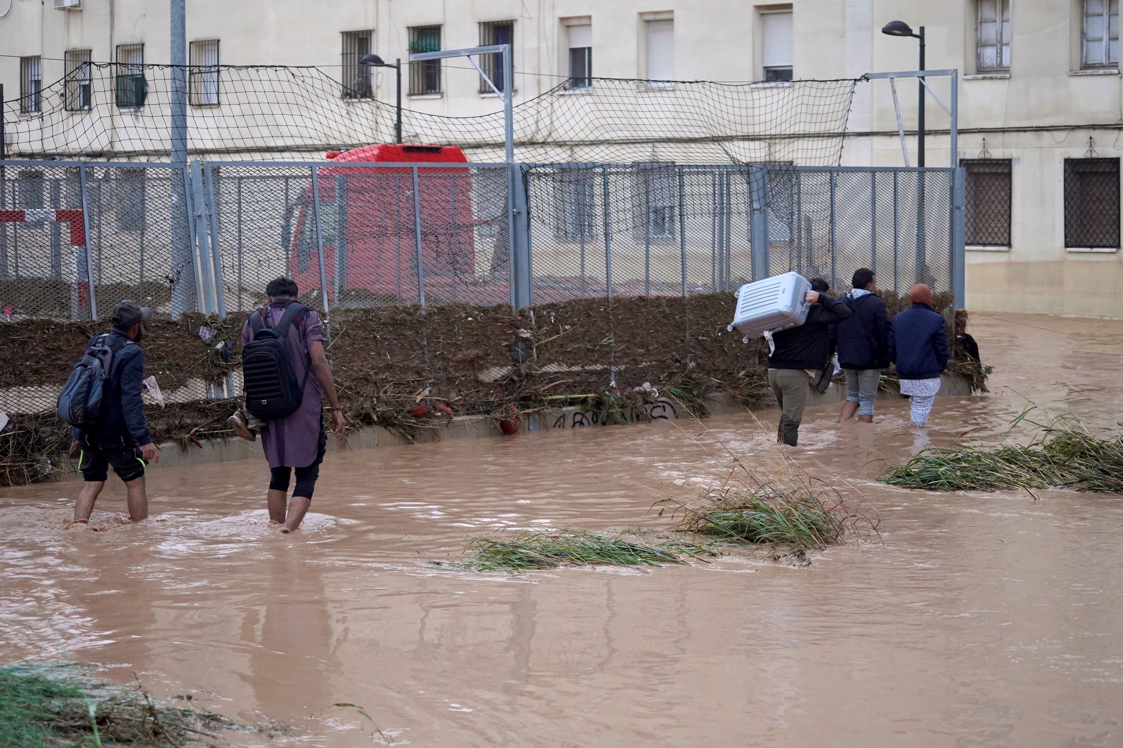 People, some with their belongings, walk through flooded streets in Valencia, Wednesday, Oct. 30, 2024. (AP Photo/Alberto Saiz)