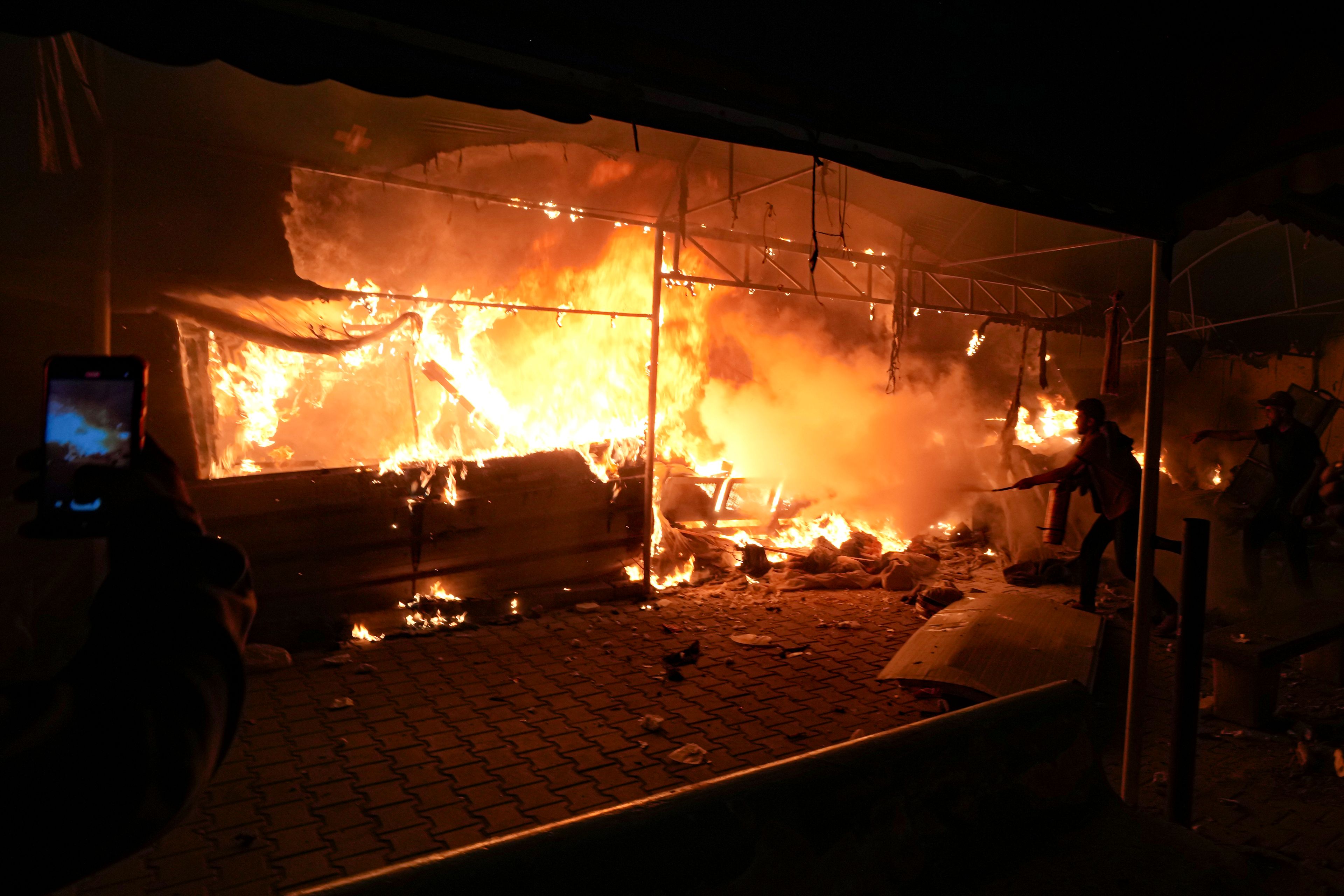 Palestinians try to extinguish fire caused by an Israeli strike that hit a tent area in the courtyard of Al Aqsa Martyrs hospital in Deir al-Balah, Gaza Strip, Monday, Oct. 14, 2024. (AP Photo/Abdel Kareem Hana)