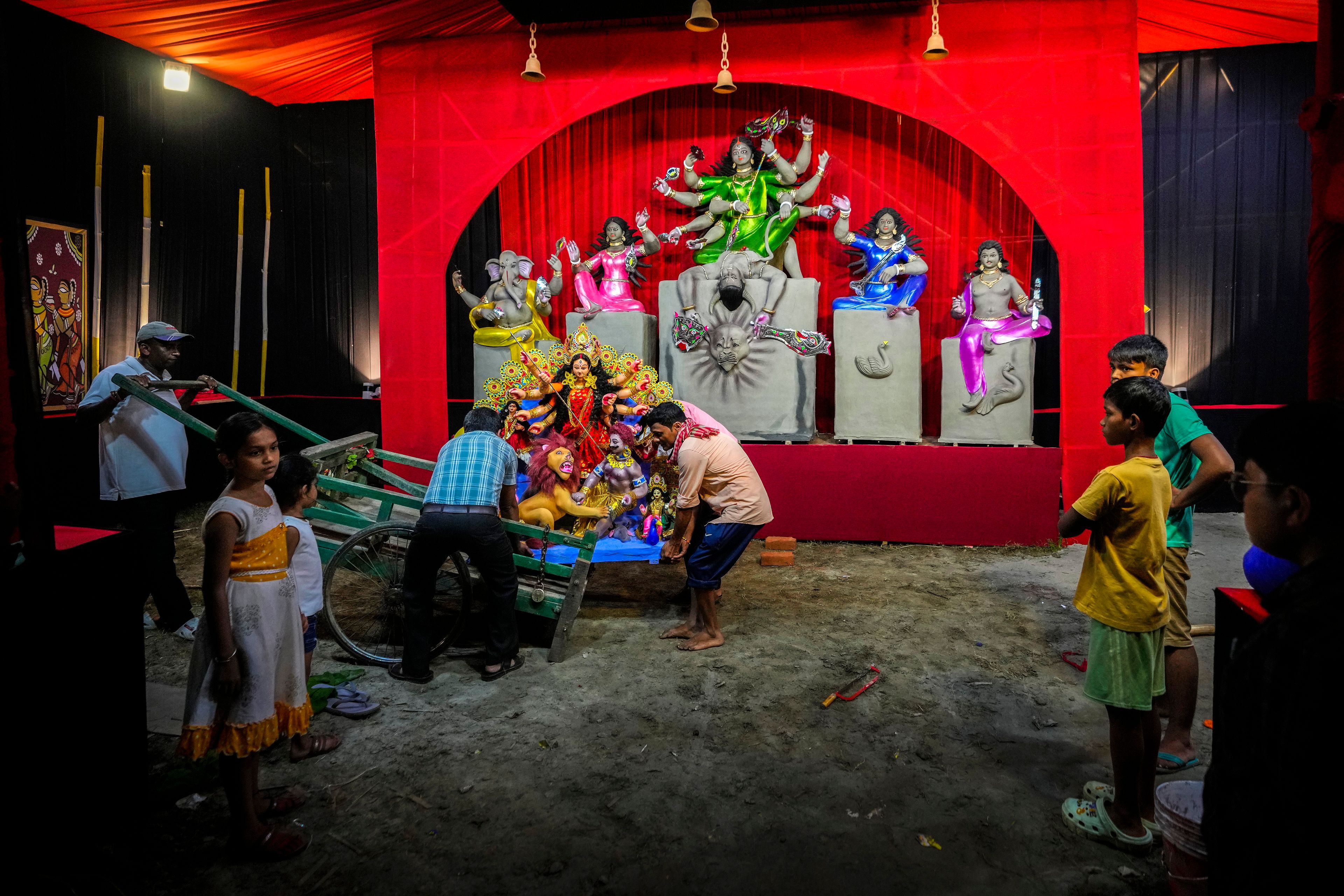 Devotees unload a mud idol of the Hindu goddess Durga from a pushcart after collecting it from a workshop during the Durga Puja festival in Guwahati, India, Tuesday, Oct. 8, 2024. (AP Photo/Anupam Nath)