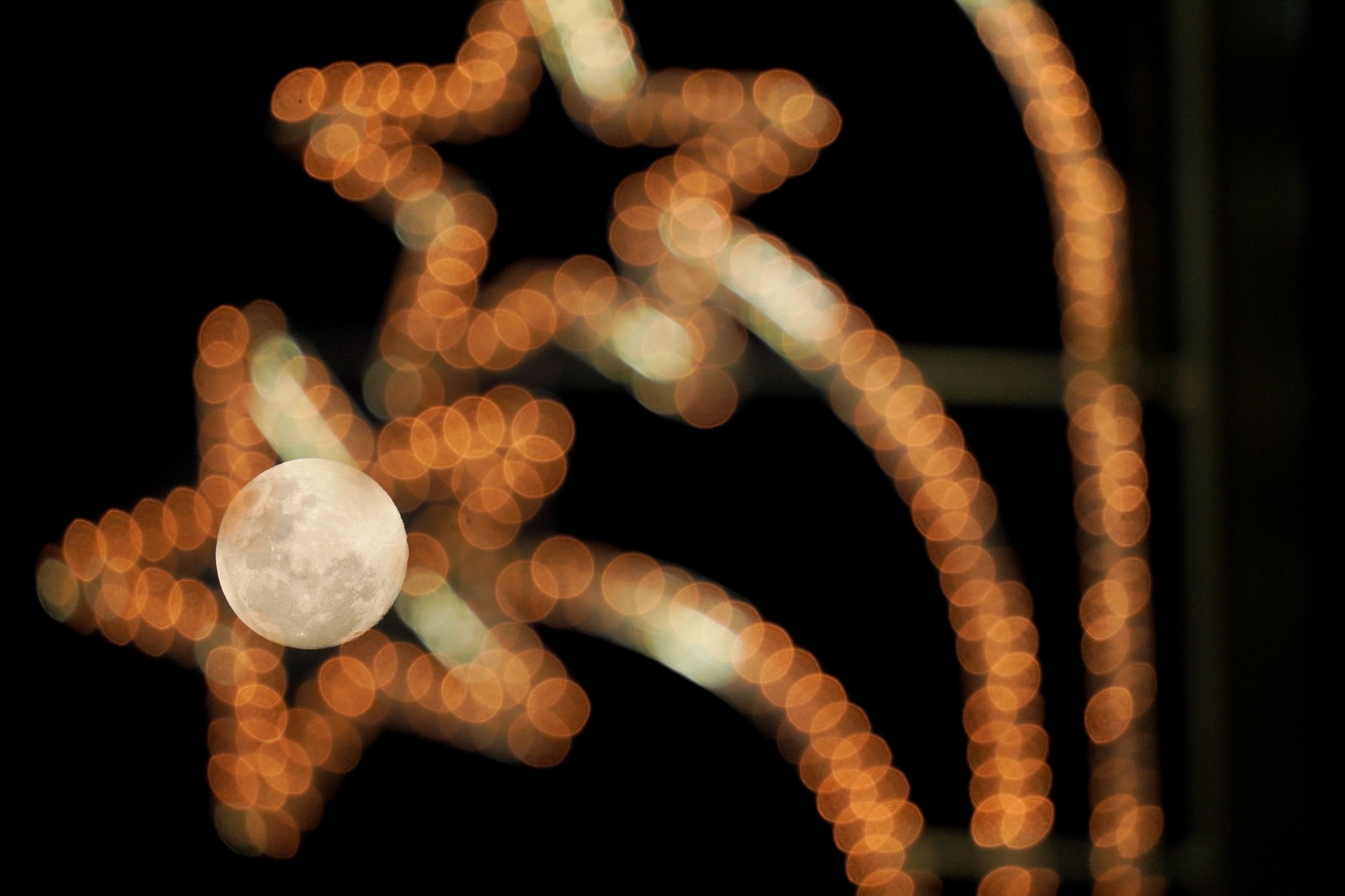 The supermoon rises behind street lights in Santiago, Chile, Thursday, Nov. 14, 2024. (AP Photo/Matias Basualdo)