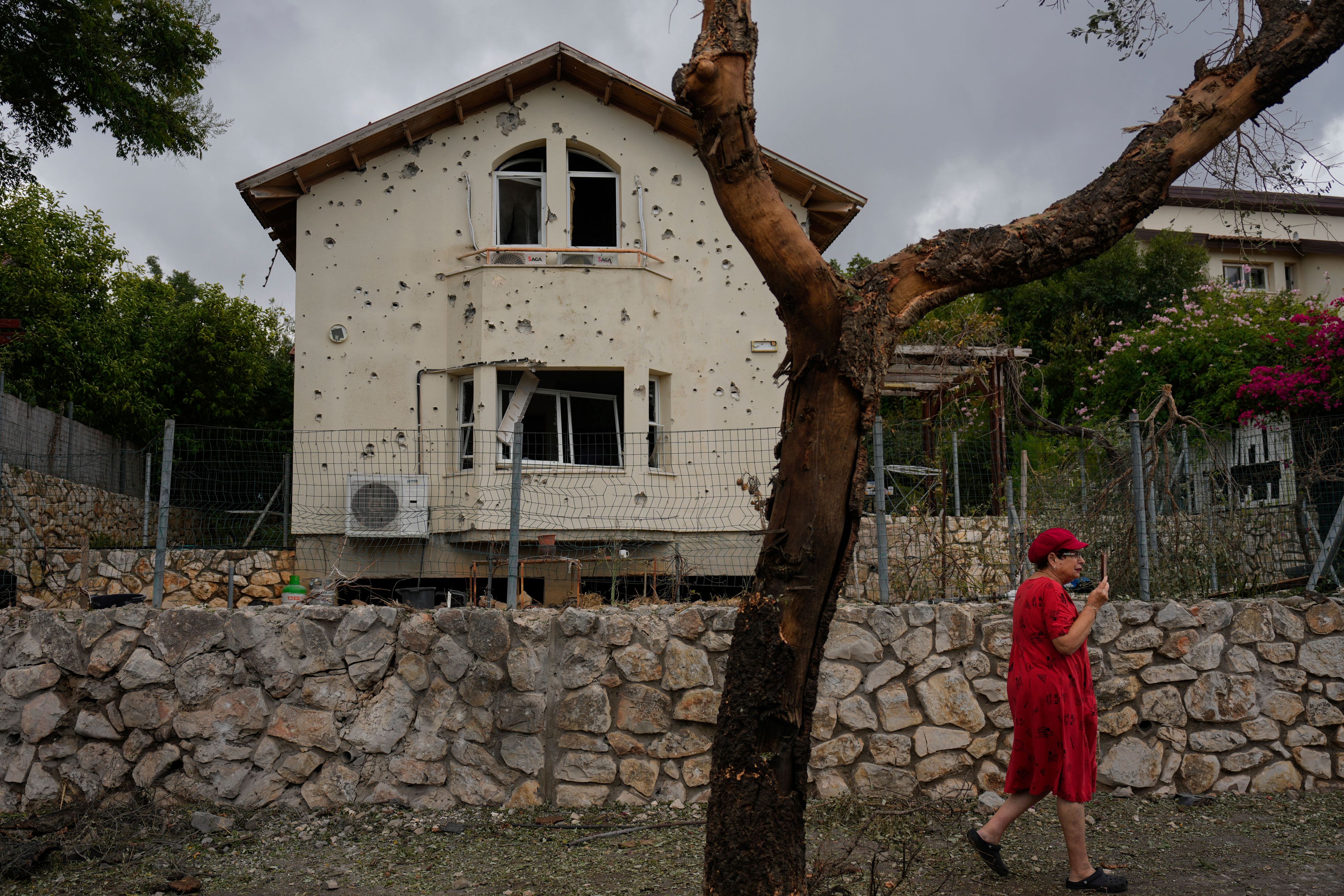 A woman walks past a house hit by a rocket fired from Lebanon, in Moreshet, northern Israel, on Sunday, Sept. 22, 2024. (AP Photo/Ariel Schalit)