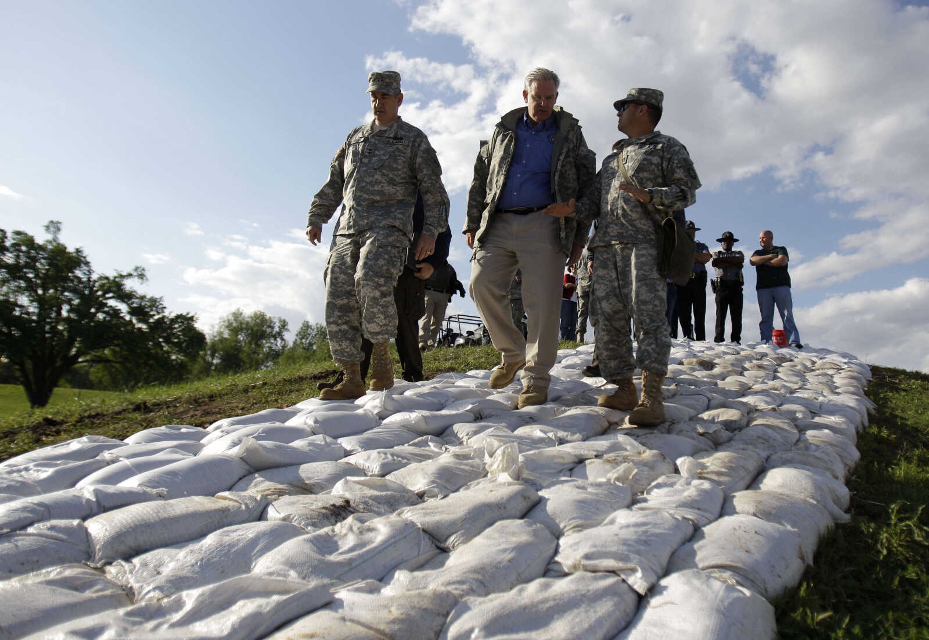 Missouri Gov. Jay Nixon walks atop a sandbag wall being built along side Maj. Gen. Stephen Danner, left, and Capt. Juan Carlos Valencia, right, both of the Missouri National Guard as they tour flood preparations Tuesday, May 3, 2011, in Caruthersville, Mo.  The town in southeast Missouri is bracing for a crest of 49.7 feet later this week. The flood wall protecting the town can hold back up to 50 feet, but a sustained crest will pressure the wall. Workers have been fortifying the concrete and earthen barrier with thousands of sand bags. (AP Photo/Jeff Roberson)