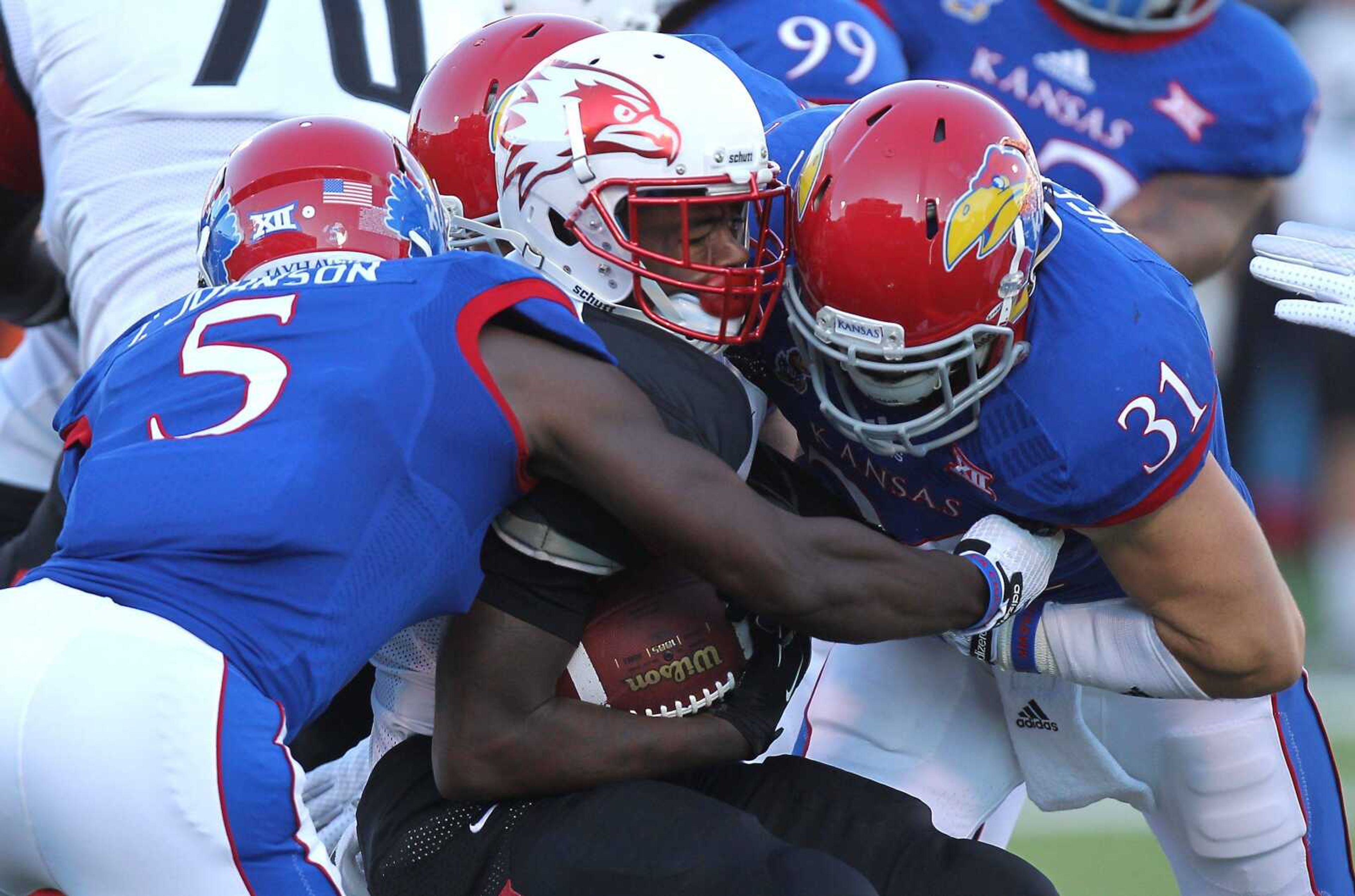 Southeast Missouri St. running back DeMichael Jackson, center, is tackled by Kansas&#8217; Isaiah Johnson (5) and Ben Heeney (31) during the first quarter Saturday in Lawrence, Kansas. (Ed Zurga ~ Associated Press)