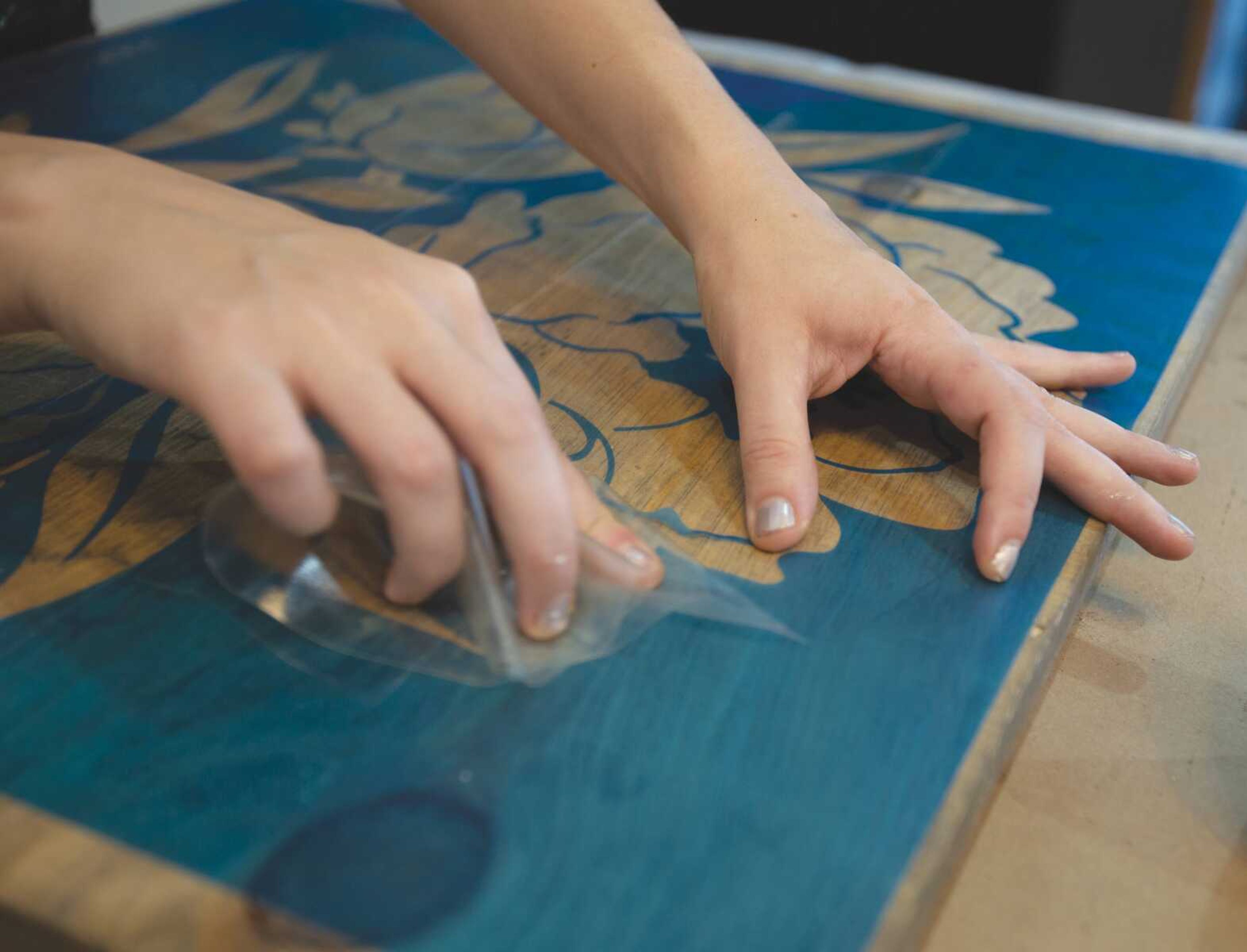 Brittney Swicionis peels a stencil off an art project. Swiconis says customers assemble, stain, sand, distress and paint their own wood signs, with instruction from a Board & Brush teacher. 