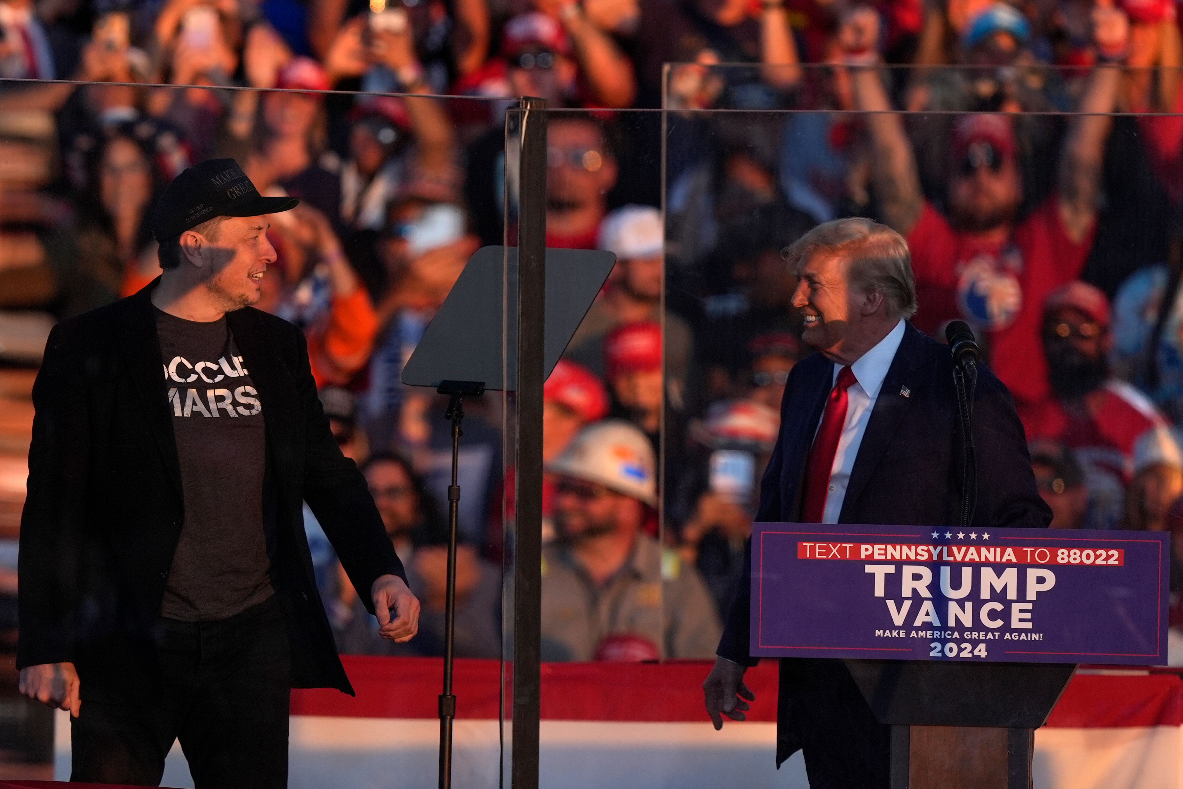 Elon Musk jumps on the stage behind Republican presidential nominee former President Donald Trump during a campaign rally at the Butler Farm Show, Saturday, Oct. 5, 2024, in Butler, Pa. (AP Photo/Julia Demaree Nikhinson)