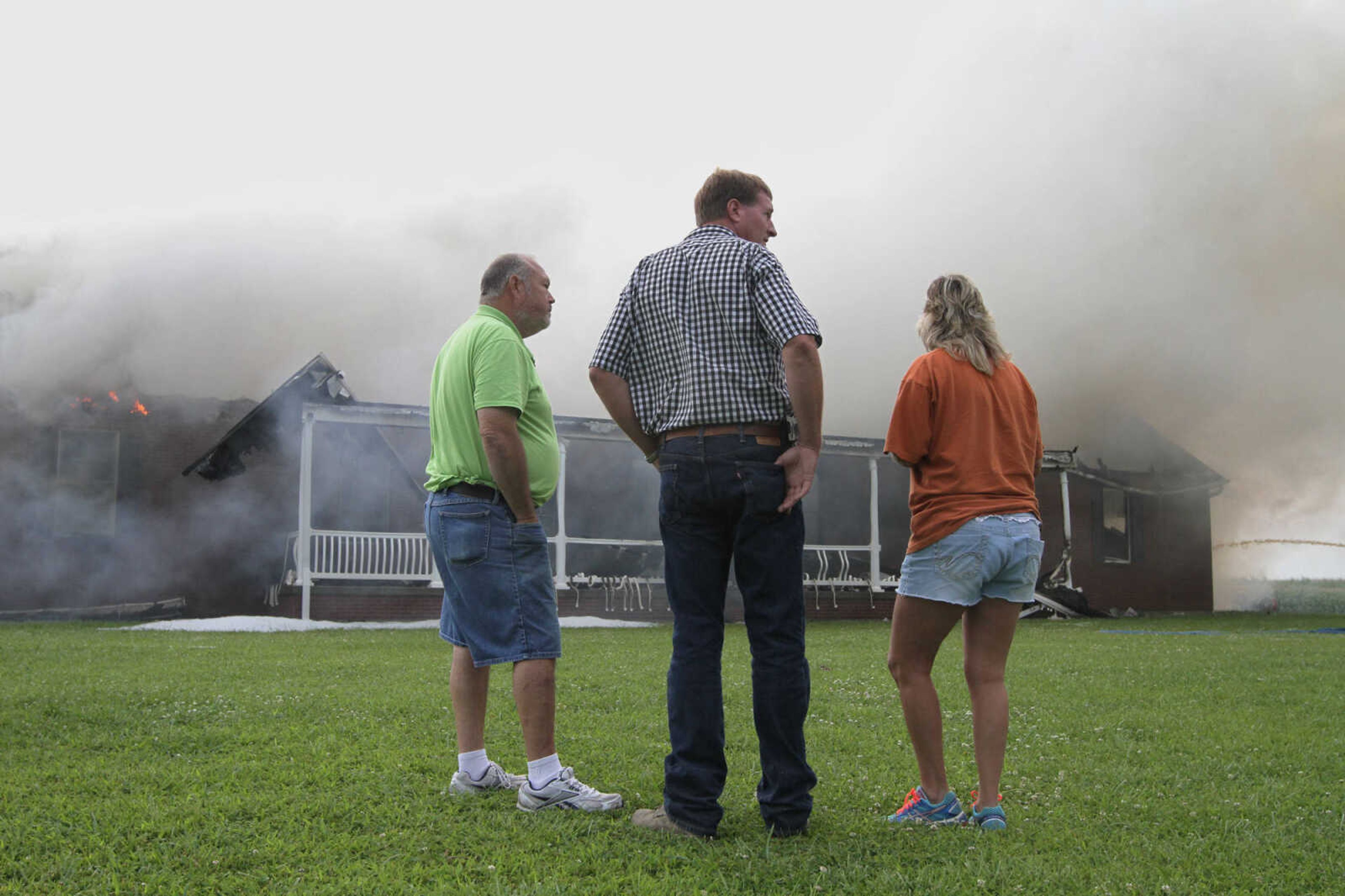 GLENN LANDBERG ~ glandberg@semissourian.com

David Landewee, center, stands with friends and family while his house smolders after the fire Wednesday, July 23, 2014 in Scott Country.