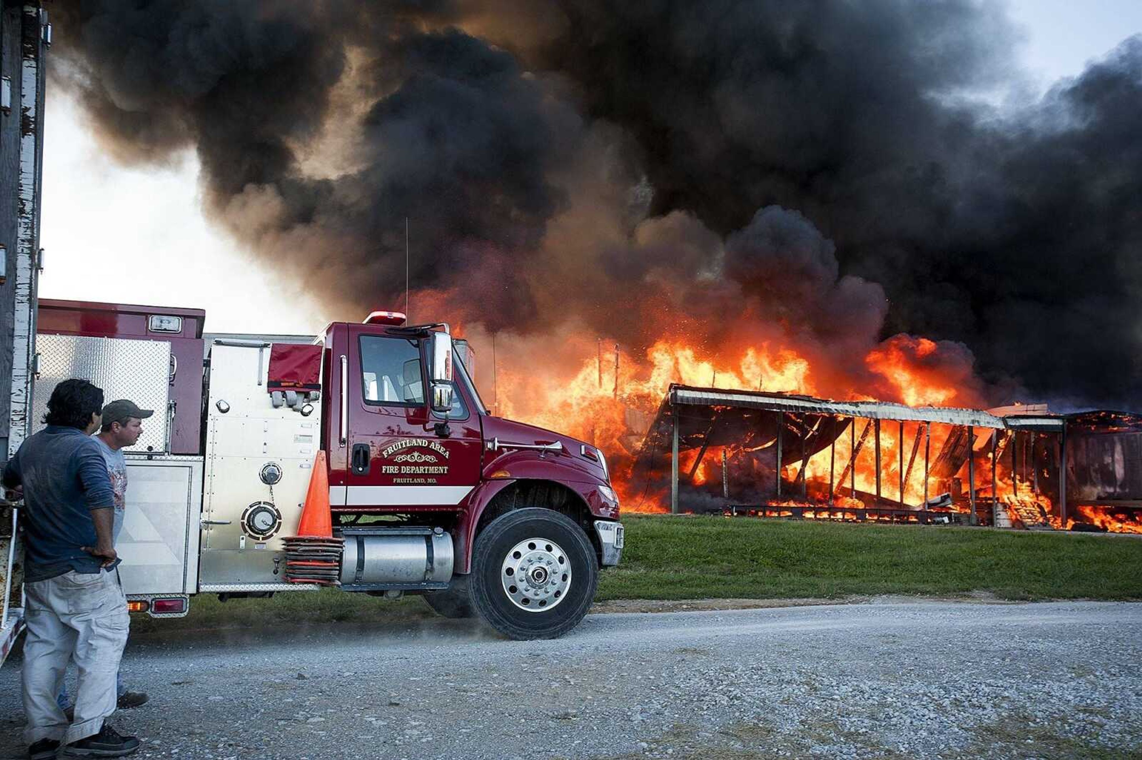 Bystanders watch as firefighters from at least six area fire departments battled a fire Tuesday at Flickerwood Farms Inc, 3027 Larch Lane in Fruitland. No one was injured in the fire which destroyed the building that house a baled wood shaving and feed byproduct business. (Adam Vogler)