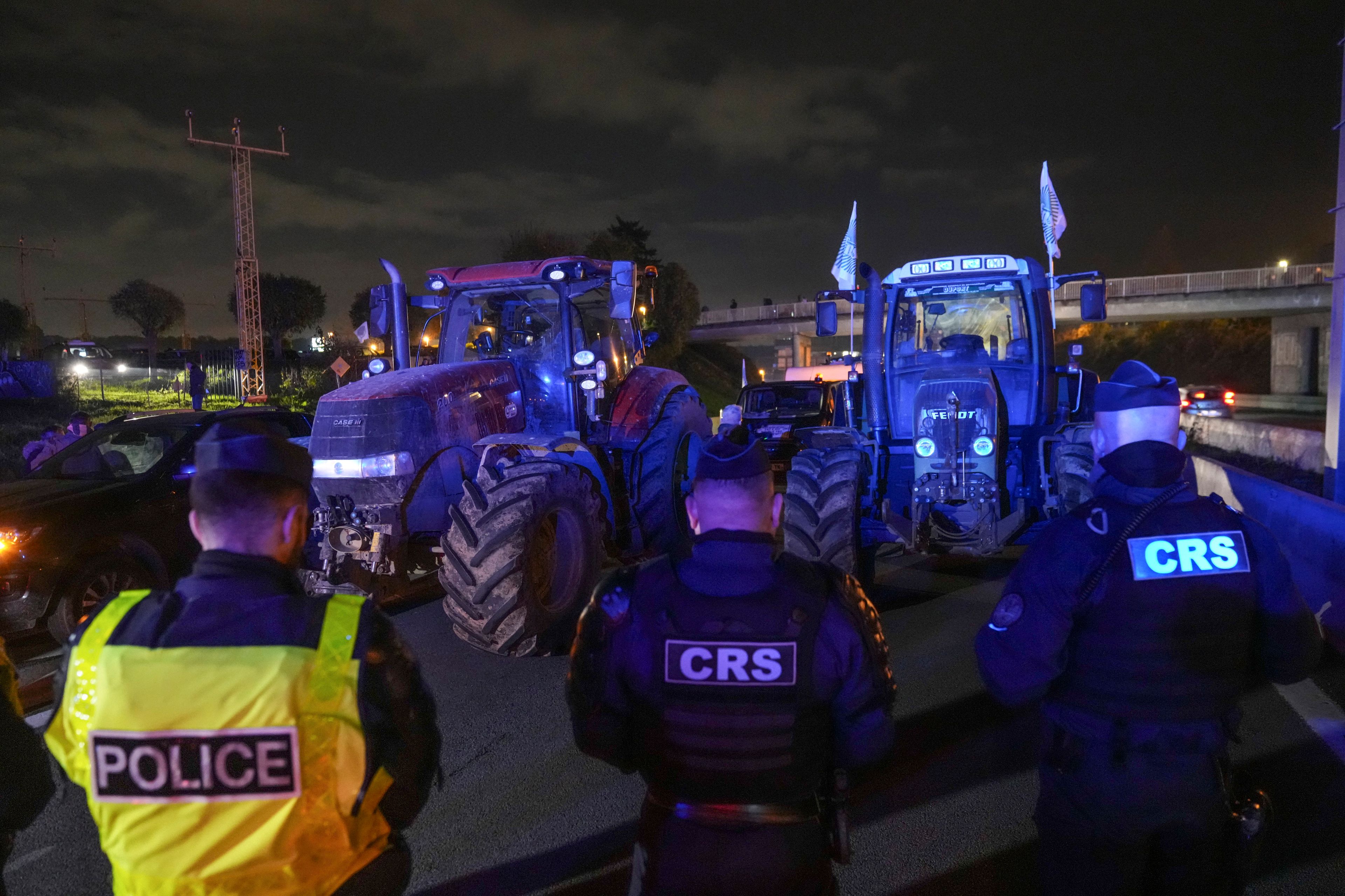 Police officers stand in front of tractors on a blocked highway in Velizy-Villacoublay, outside Paris, Sunday, Nov. 17, 2024. (AP Photo/Michel Euler)