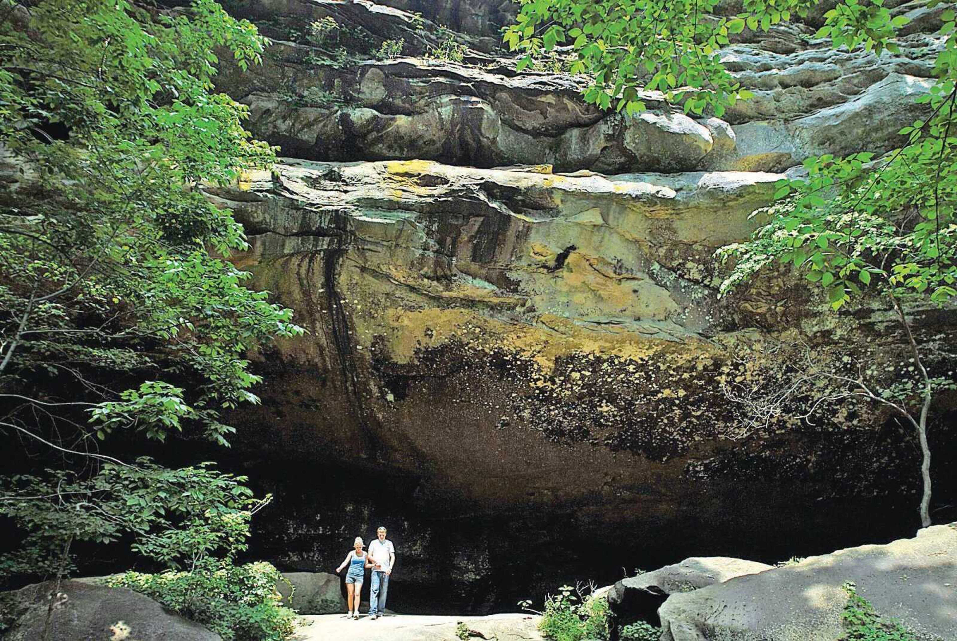 Jennifer Medlin and Nathan Hastings walk out from under a massive rock cliff on the Devil's Standtable Trial at Giant City State Park. (Southeast Missourian file)