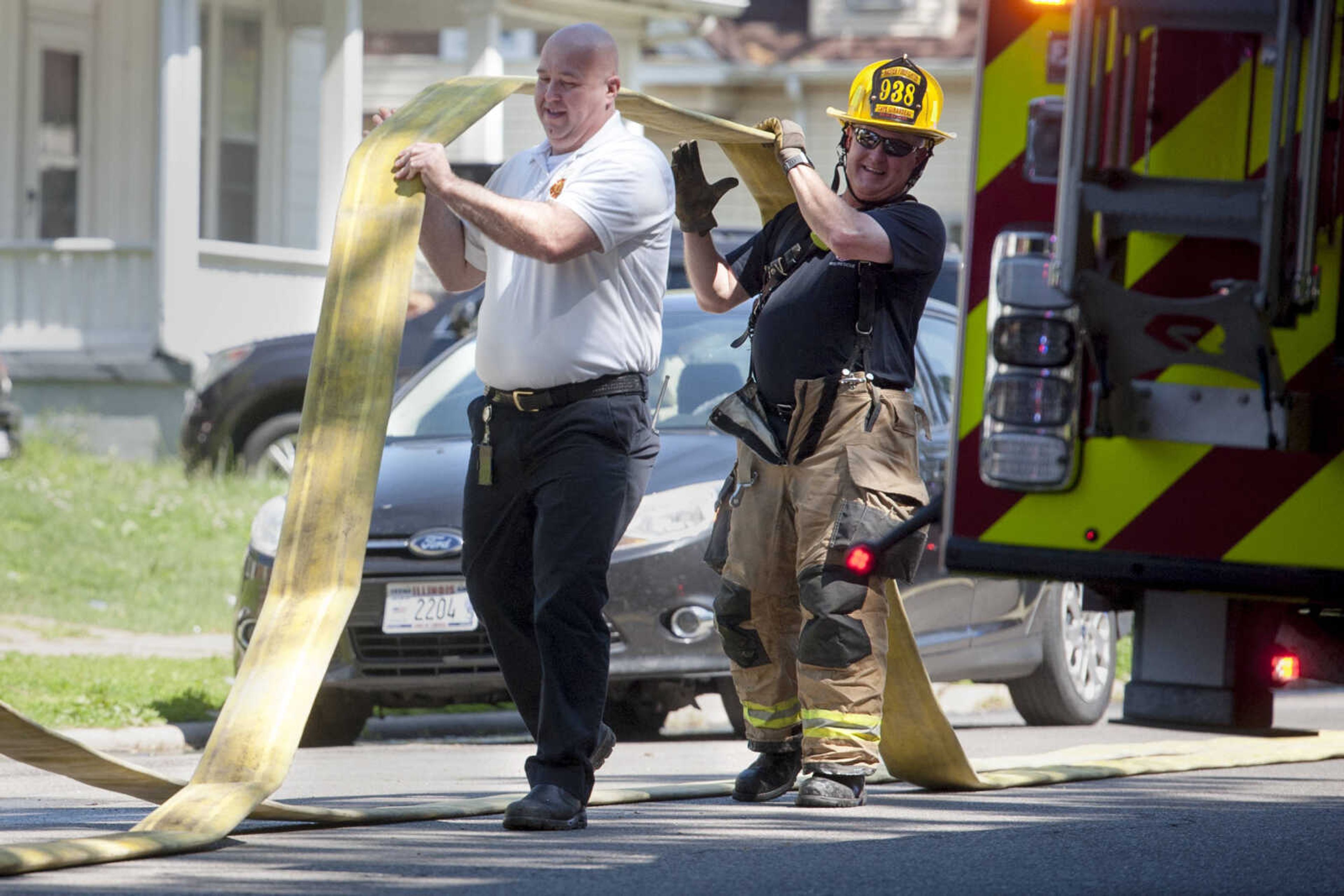 Cape Girardeau fire chief Travis Hollis carries a line with Larry Hagan, right, after extinguishing a structure fire Monday, May 11, 2020, at 40 North Henderson Ave. in Cape Girardeau.