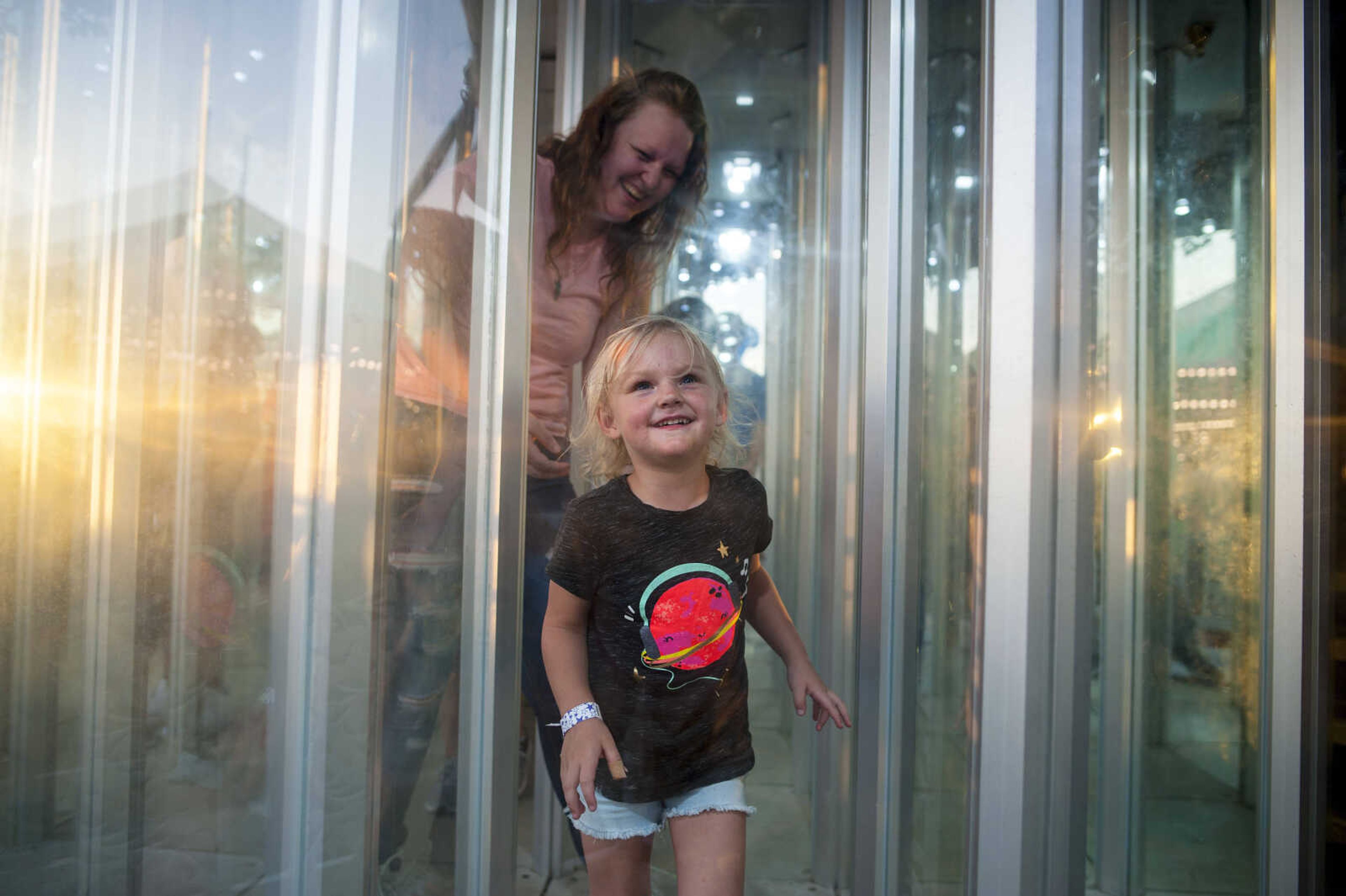 After running into a transparent funhouse wall, 3-year-old Lillian Prasun of Cape Girardeau continues in her attempts to navigate the mirror maze with her mother Hannah Wiggs on Tuesday, Sept. 10, 2019, during the SEMO District Fair at Arena Park in Cape Girardeau.