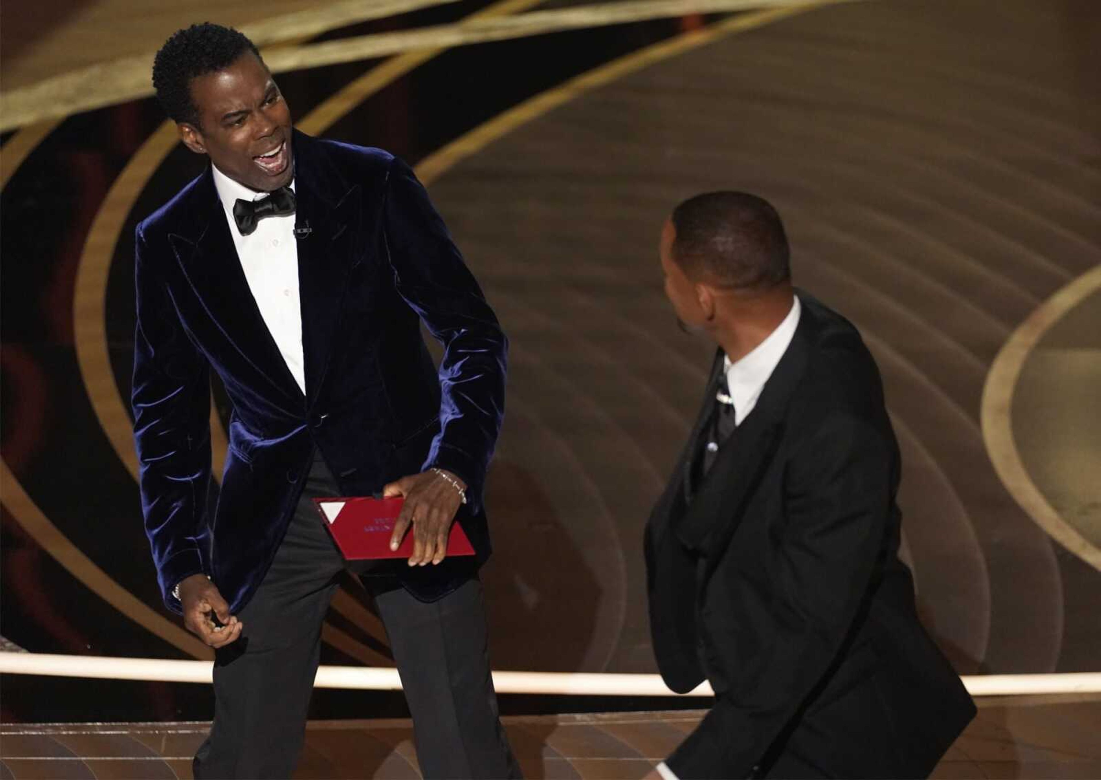 Presenter Chris Rock, left, reacts after being hit on stage by Will Smith while presenting the award for best documentary feature at the Oscars on March 27 at the Dolby Theatre in Los Angeles.