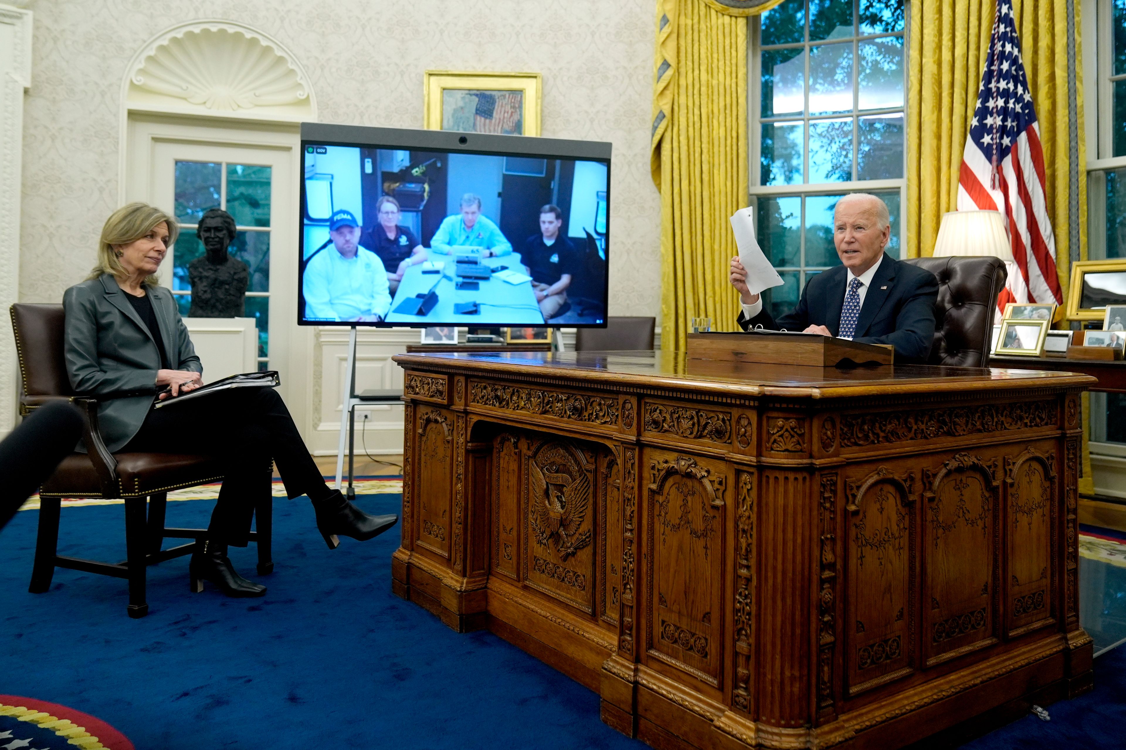 President Joe Biden, right, and White House Homeland Security Advisor Liz Sherwood-Randall, left, speak with North Carolina Gov. Roy Cooper, on screen at center right, and Administrator of the U.S. Federal Emergency Management Agency Deanne Criswell, onscreen at center left, about the Biden administration's efforts to aid in recovery from the aftermath of Hurricane Helene from the Oval Office of the White House in Washington, Monday, Sept. 30, 2024. (AP Photo/Mark Schiefelbein)