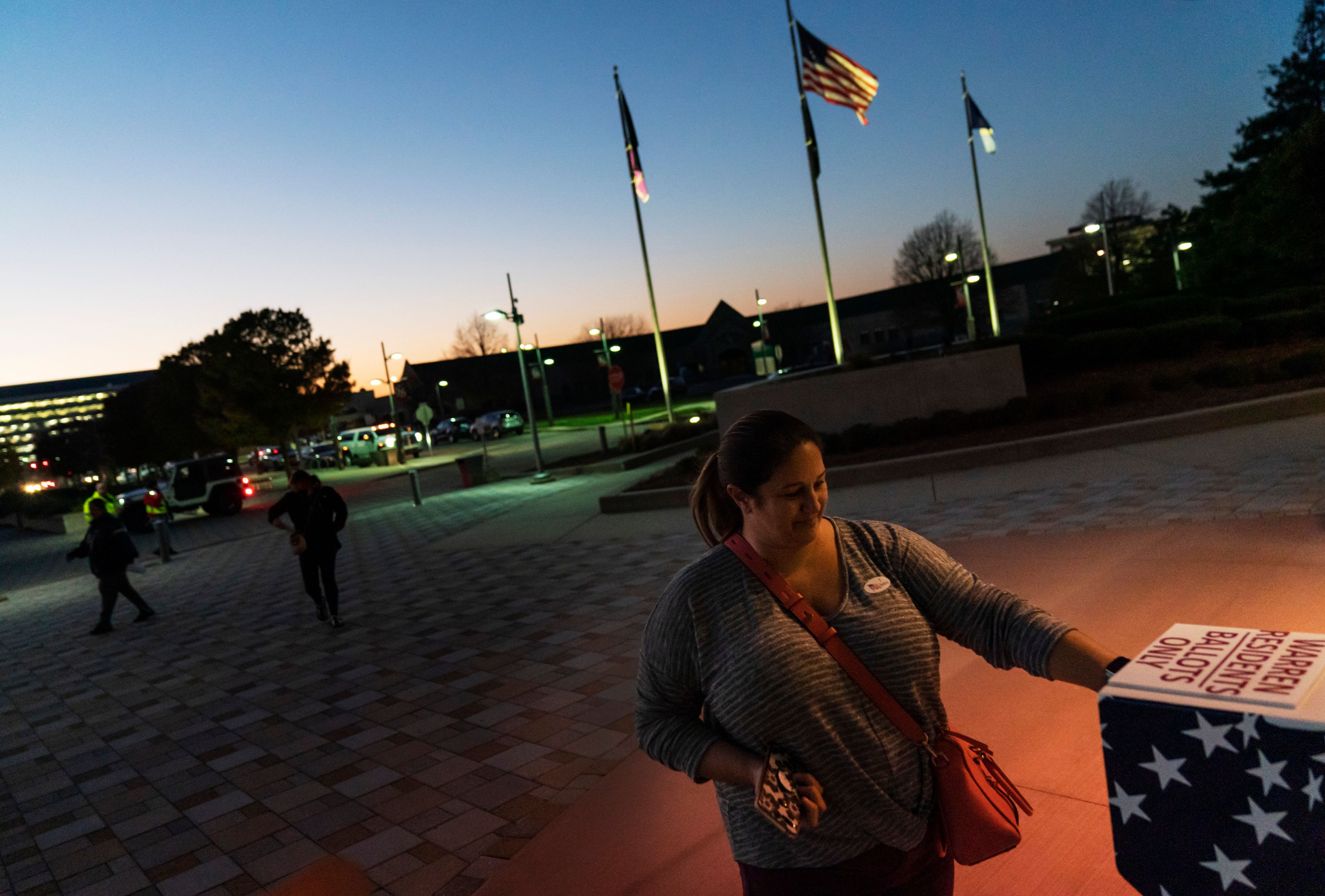 FILE - Wendy Gill inserts her absentee ballot at a drop-off box as the sun sets on Election Day outside City Hall in Warren, Mich., Nov. 3, 2020. (AP Photo/David Goldman, File)