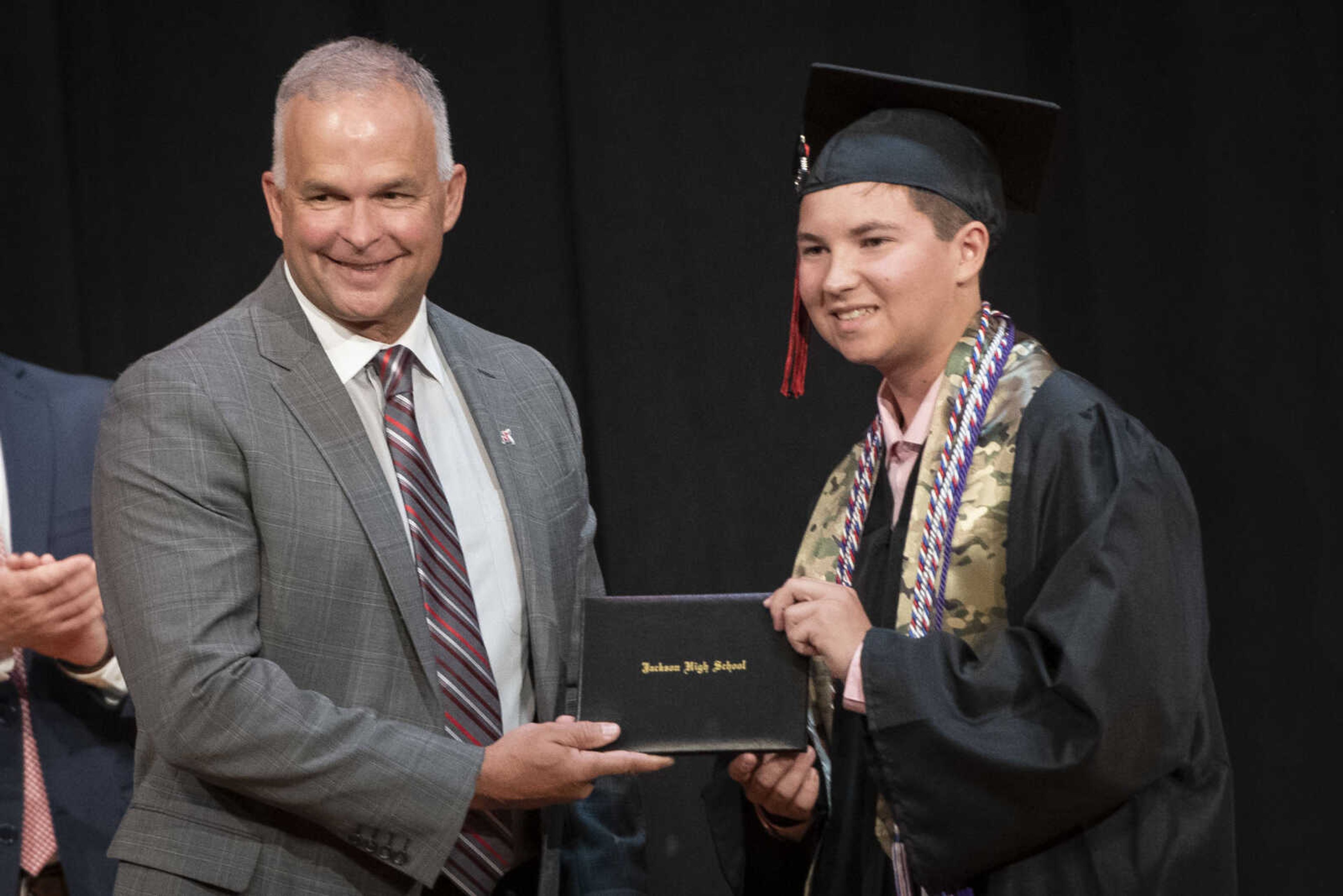 Jackson High School graduate Logan Wayne McClanahan has a picture made with Kelly Waller, president of the board of education, during an in-person military graduation ceremony Friday, May 22, 2020, at Jackson High School.