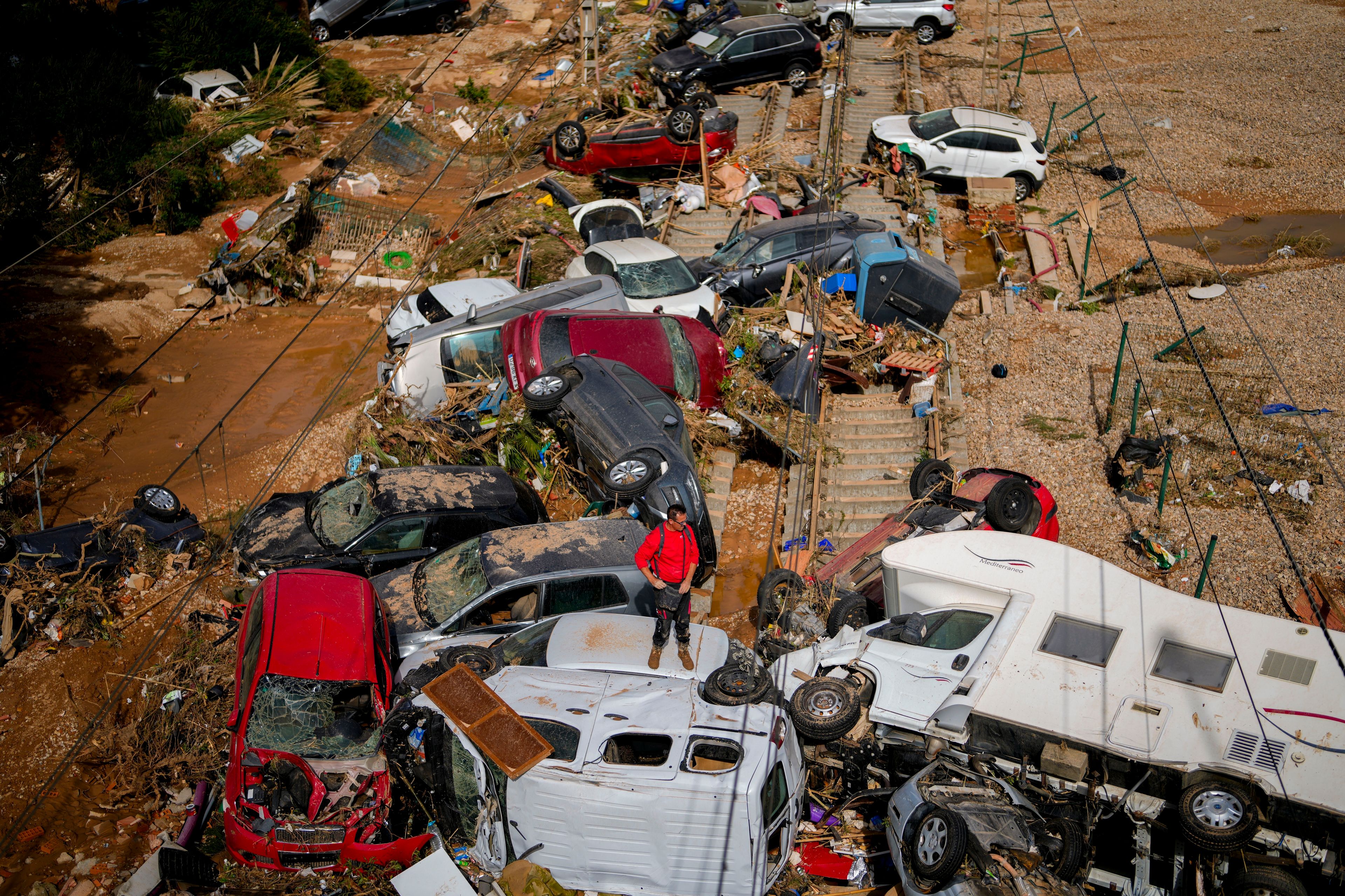 A man stands among flooded cars piled up in Valencia, Spain, Thursday, Oct. 31, 2024. (AP Photo/Manu Fernandez)