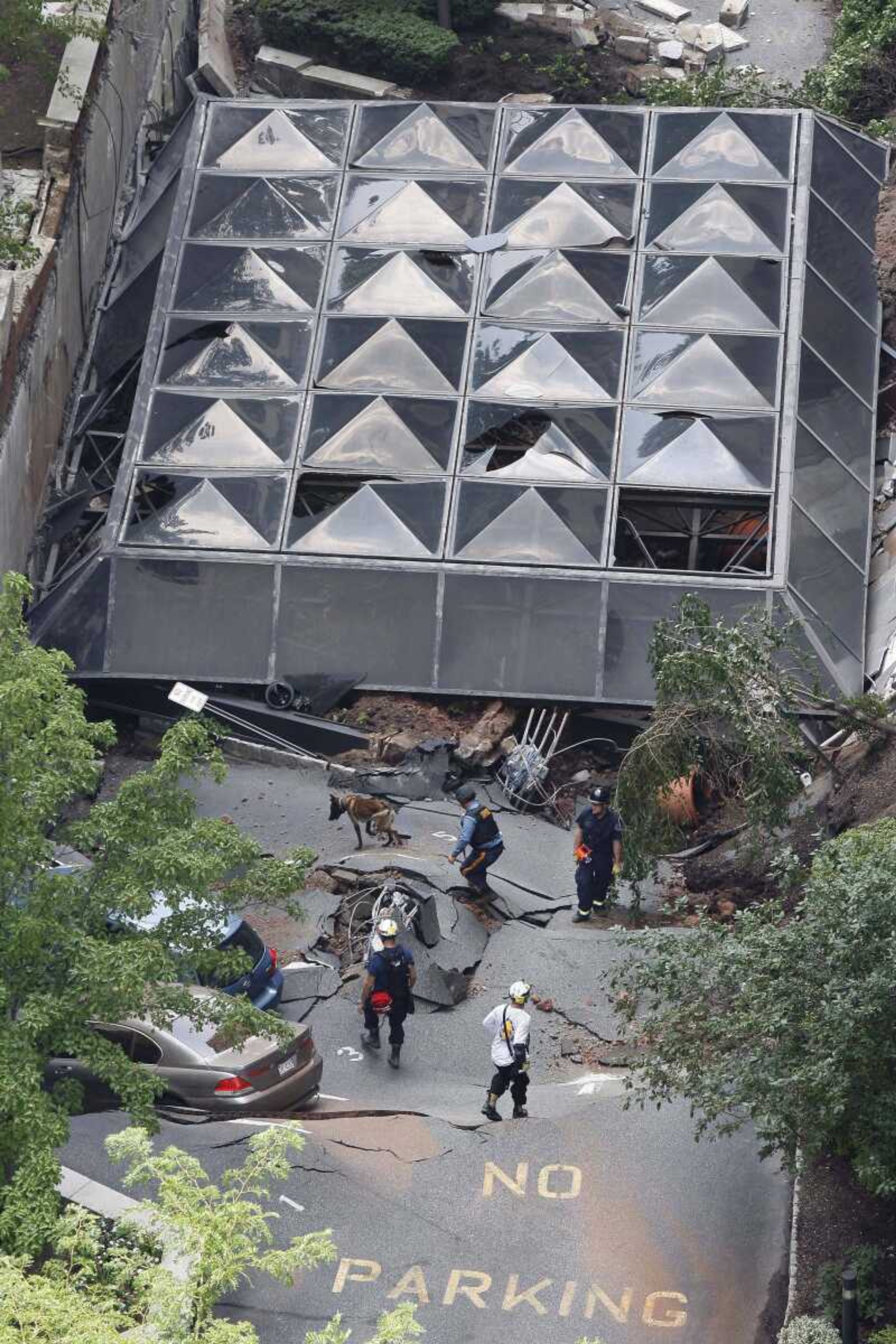 A police officer works with a search dog as other rescue officials walk on the rubble after the front of an apartment building and a parking garage collapsed Friday, in Hackensack, N.J. A glass canopy attached to a high-rise condominium building fell onto a parking garage two stories below on Friday, authorities said. (MEL EVANS ~ Associated Press)