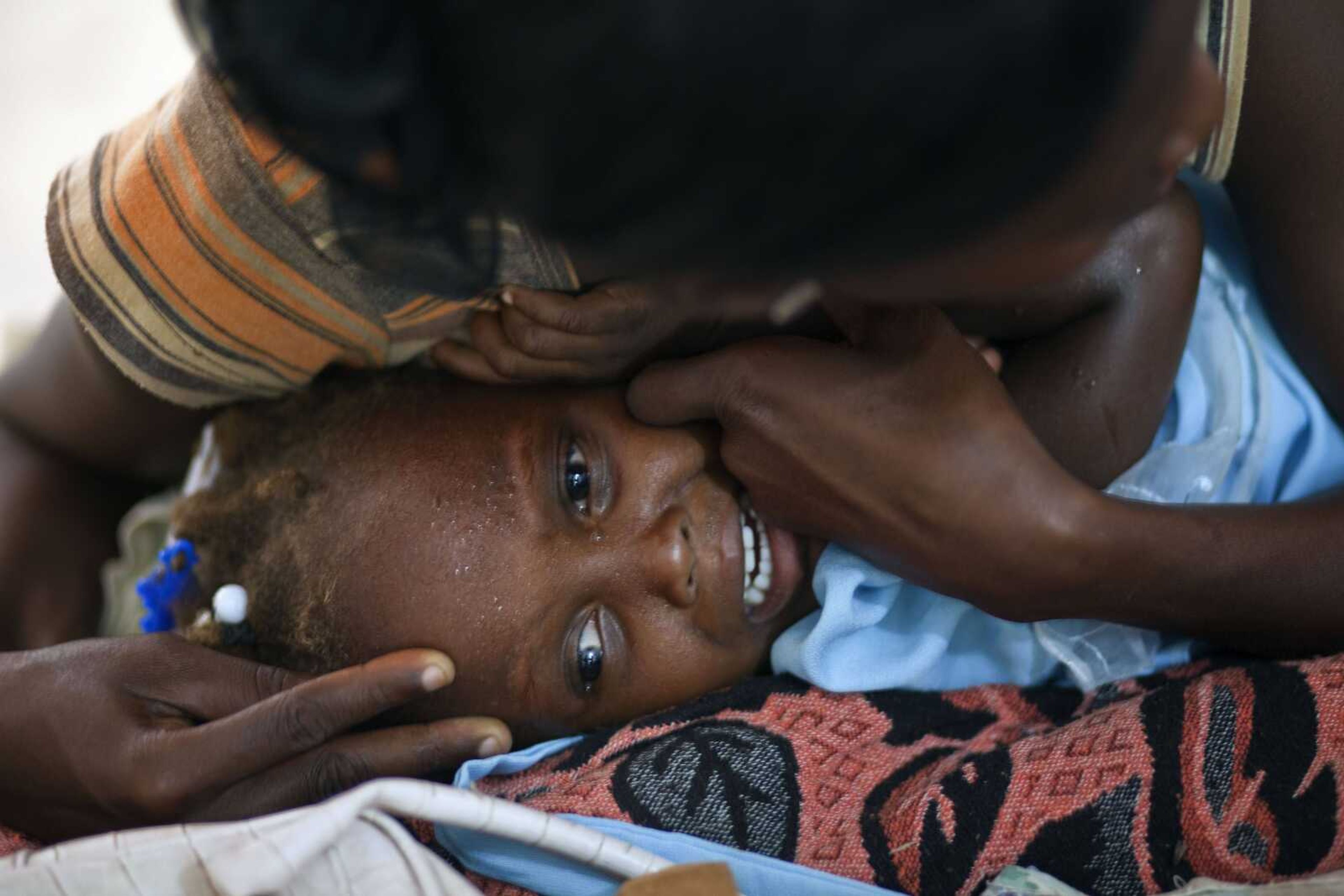 A child suffering cholera symptoms cries Saturday as she is comforted by a woman at a hospital in Grande-Saline, Haiti. A spreading cholera outbreak in rural Haiti threatened to outpace aid groups as they stepped up efforts hoping to keep the disease from reaching the camps of earthquake survivors in Port-au-Prince. (Ramon Espinosa ~ Associated Press)