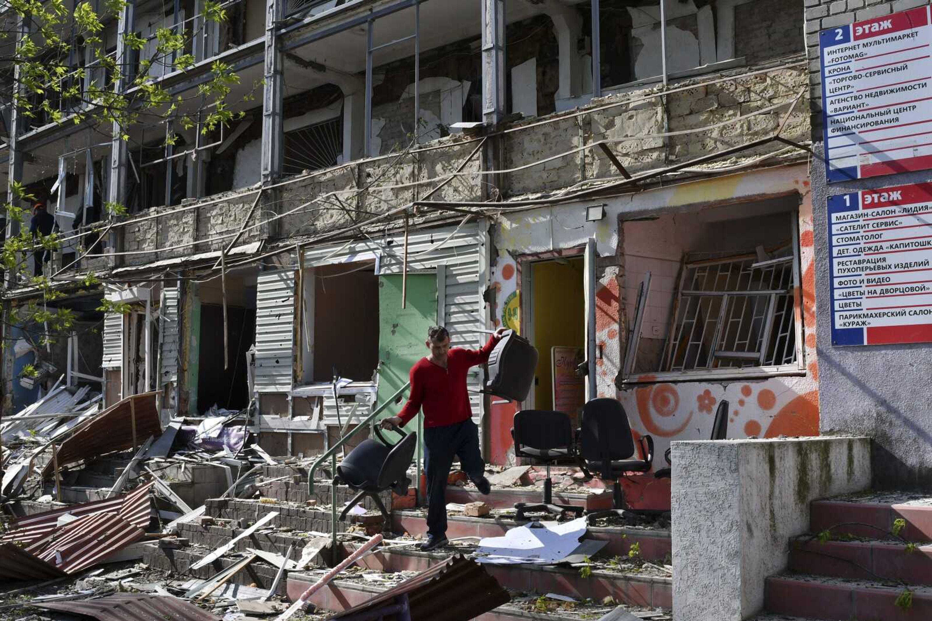 A man carries chairs Thursday out of an office on a ground floor of an apartment building destroyed by night shelling in Kramatorsk, Ukraine.