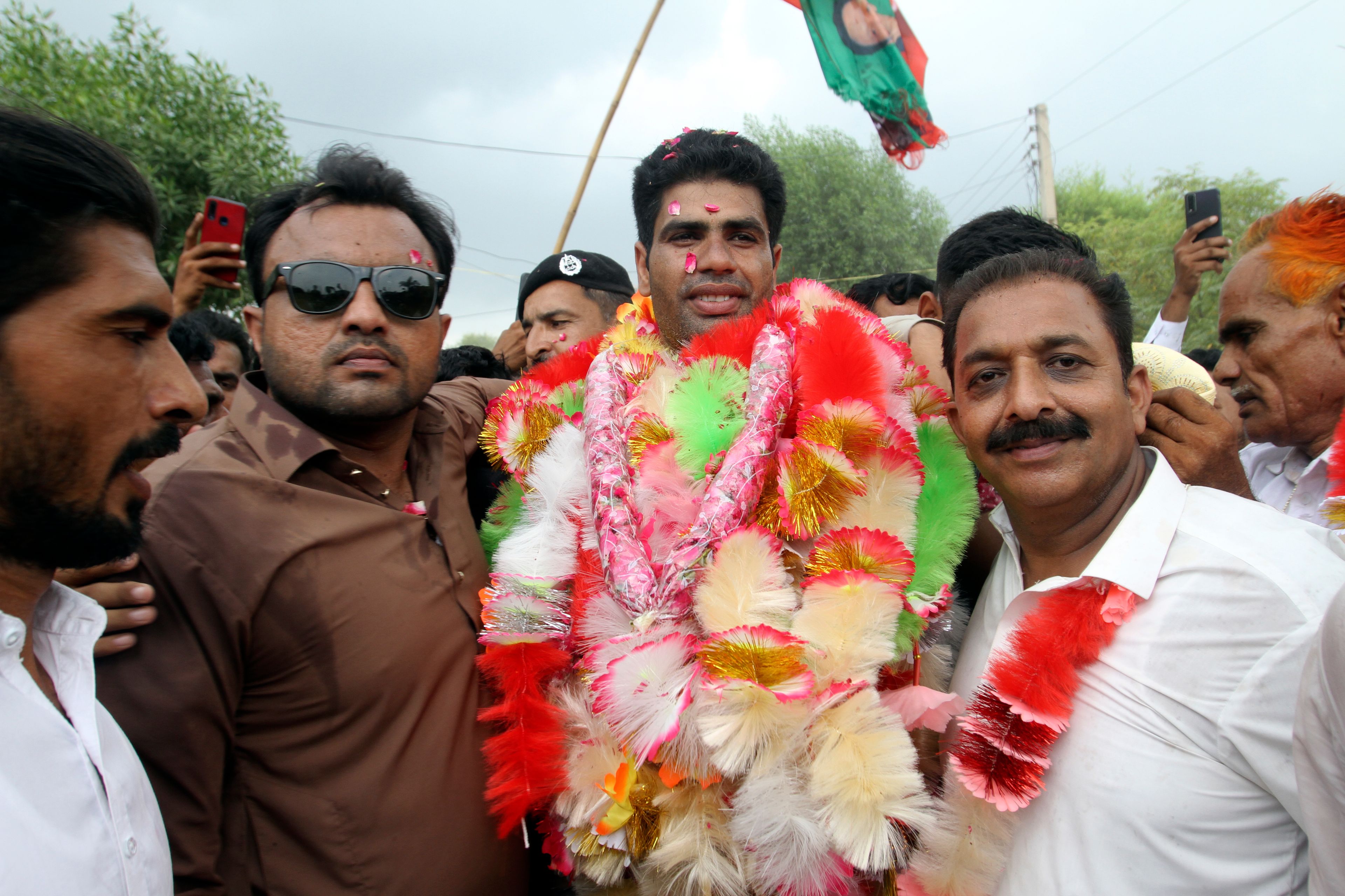 Pakistan's javelin gold medalist, Arshad Nadeem, center, is greeted by Pakistani people and his villagers with flower garlands upon his arrival at Mian Channu, Khanewal district, of Pakistan, Sunday, Aug. 11, 2024. (AP Photo/Asim Tanveer)