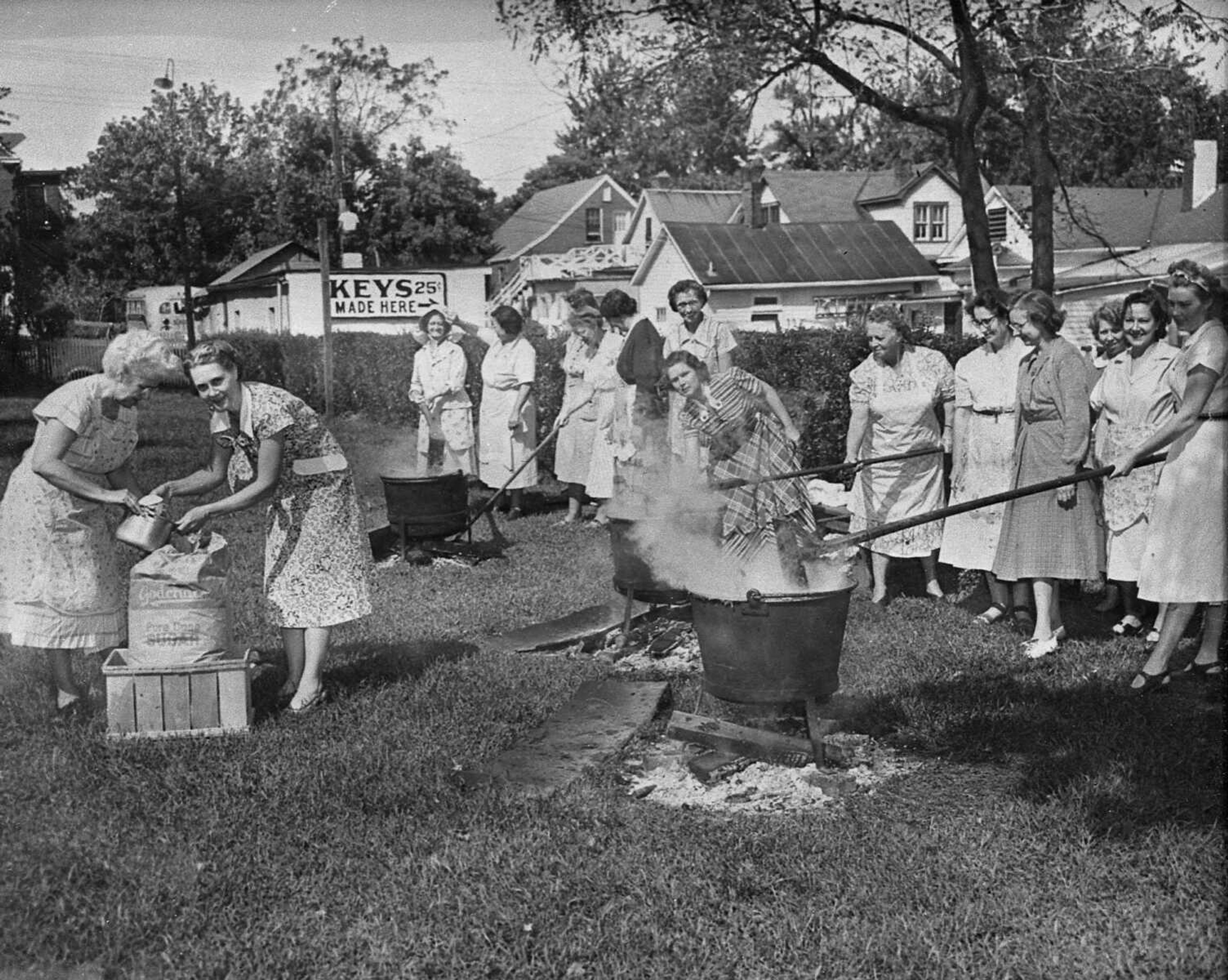 Sept. 28, 1951 Southeast Missourian.
With their three big copper-lined kettles and a good wood fire, these Grace Methodist Church women made 225 quarts of apple butter in two days and sold every bit of it. Jonathan and Gano apples went into the butter, all seasoned up with spices. From the left, starting with the women delving into the sugar sack, are Mrs. Ted Regenhardt, Mrs. W.J. McBride, Mrs. J.W. Wilkerson, Mrs. Clarence Snider, Mrs. Walter Riehn, Mrs. O.H. Northdurft, Mrs. Phil Haman, Mrs. Leon Brennecke, Mrs. Tom Sawyer, Mrs. Fred Mehrle, Mrs. R.O. Bingenheimer, Mrs. Lloyd Statler, Mrs. Lloyd Likens, Mrs. Charles Hadfield and Mrs. L.R. Hinck. (G.D. Fronabarger/Southeast Missourian archive)