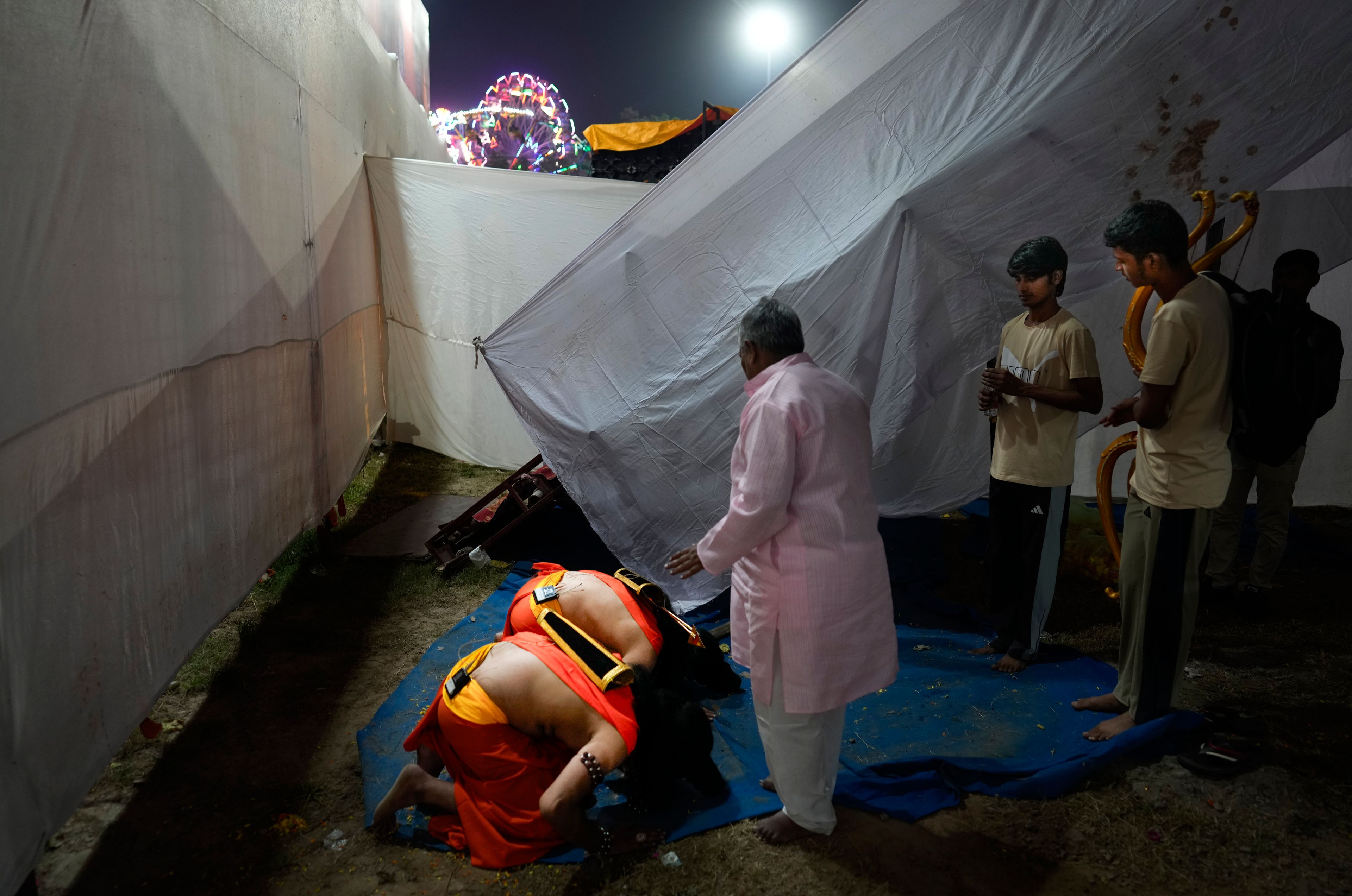 Characters playing the Hindu God Rama and his brother Laxmana touch the feet of the theatre director Rakesh Ratnakar at end of the third day of Ramleela, a dramatic folk re-enactment of the life of Rama according to the ancient Hindu epic Ramayana, in New Delhi, India, Wednesday, Oct. 9, 2024. (AP Photo/Manish Swarup)