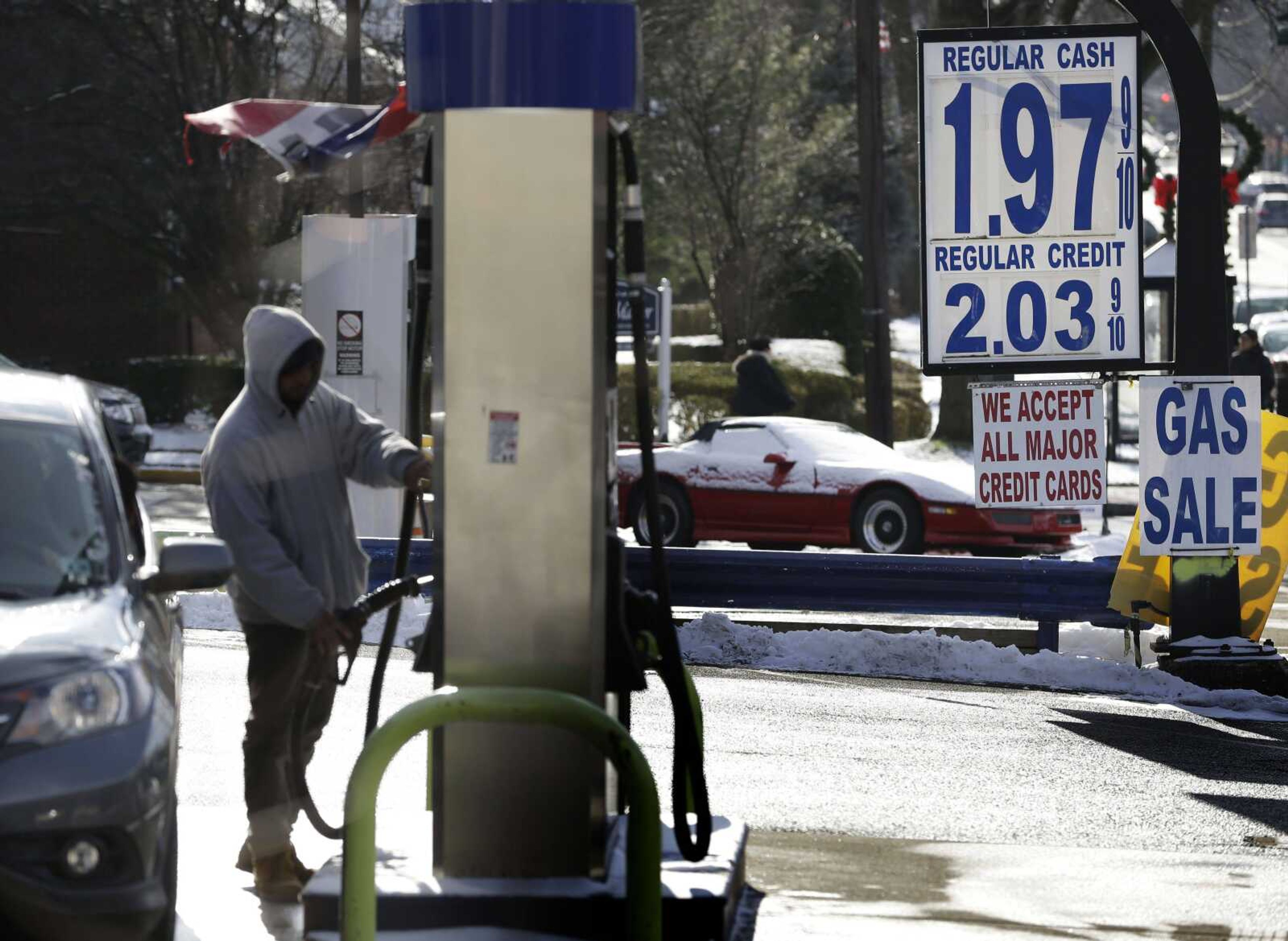 A motorist in Leonia, New Jersey, fills up his car as the price of unleaded regular fell below $2 a gallon Jan. 9. Motorists around the world have benefited from low oil prices all year. (Seth Wenig ~ Associated Press)