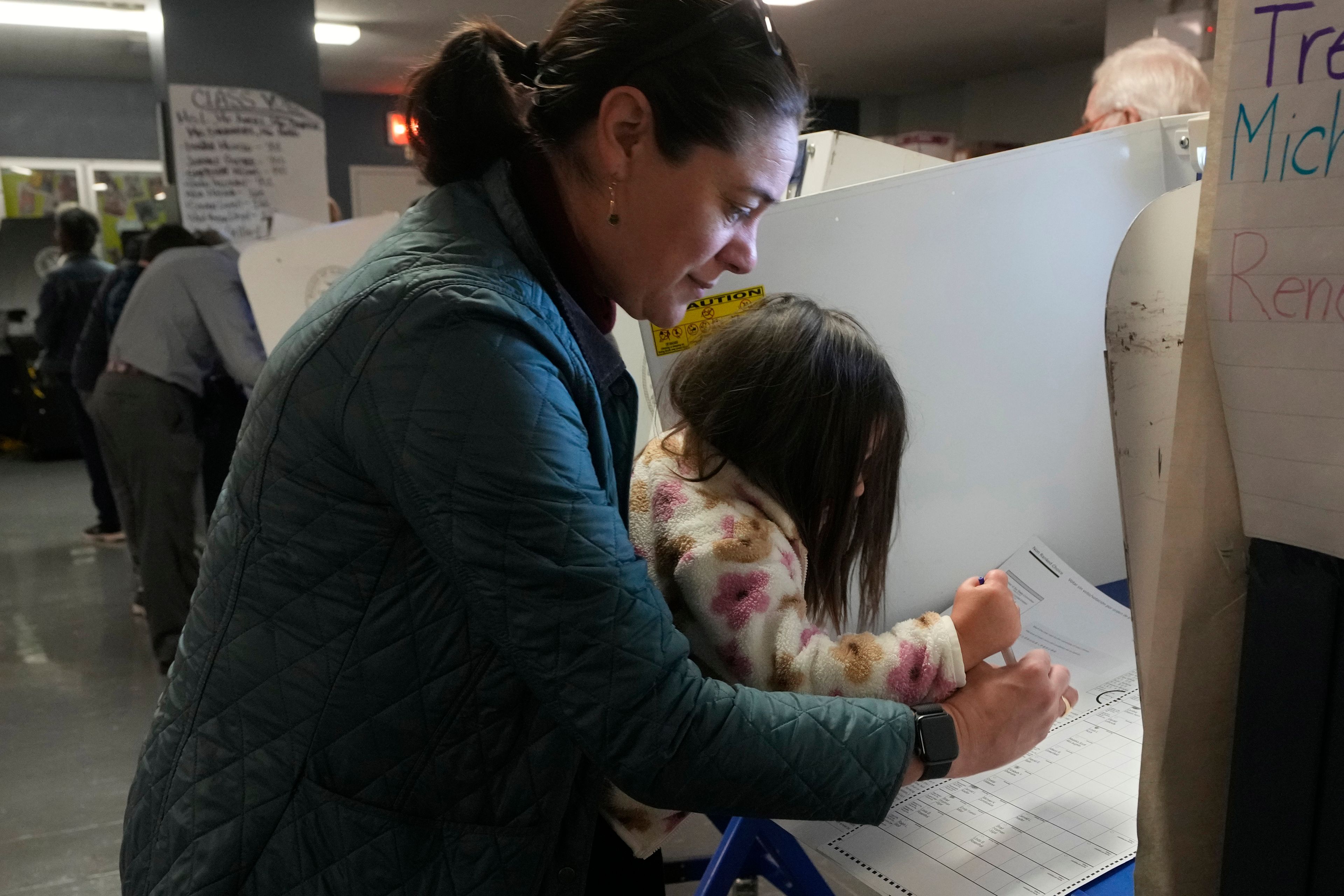 Vesta Avery, 2, helps her mother Alexis Taylor mark her ballot at P.S. M811, The Mickey Mantle School, in New York, Tuesday, Nov. 5, 2024. (AP Photo/Richard Drew)