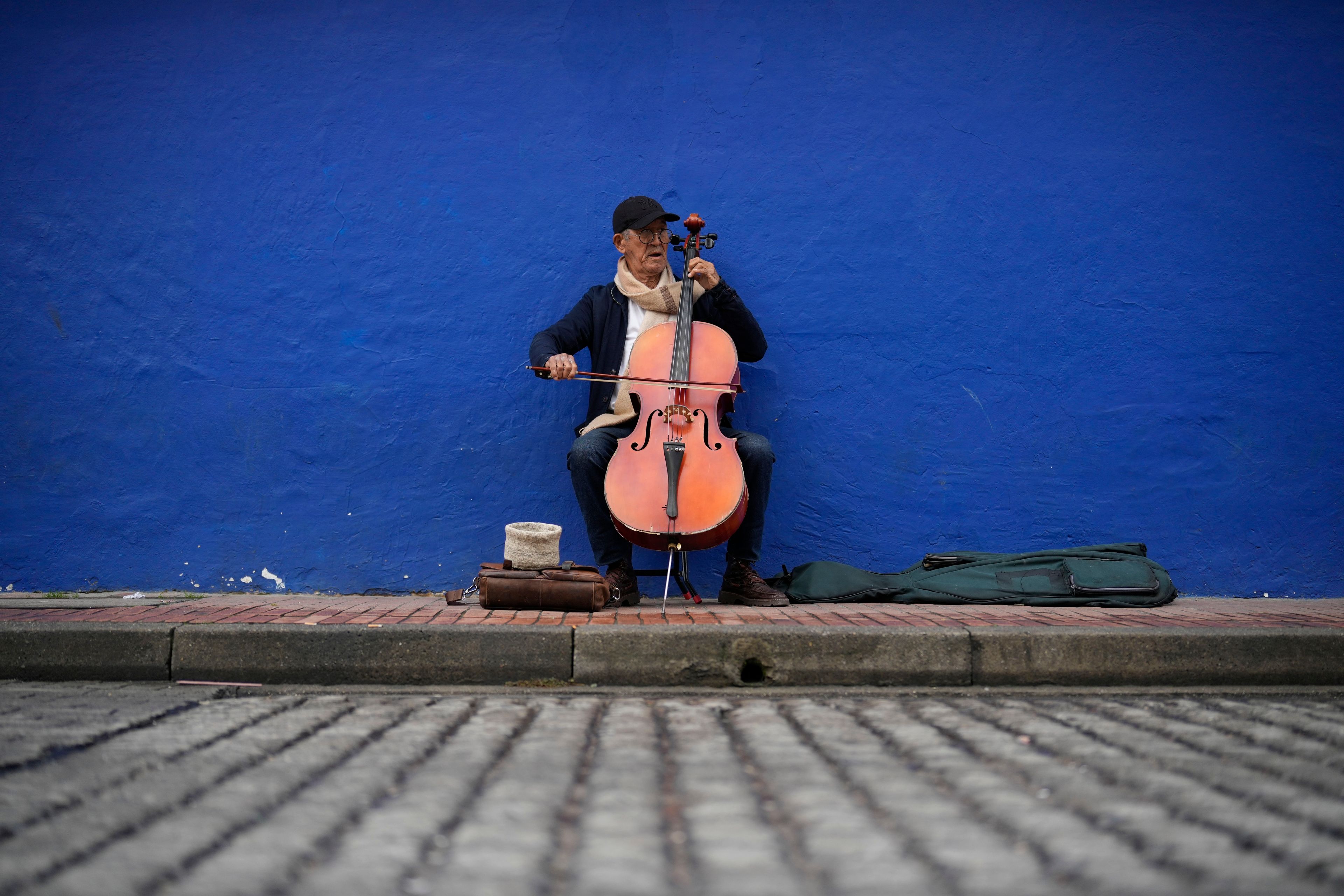 Fabio Guarin, 78, an amateur musician, plays the cello for tips in La Candelaria neighborhood of Bogota, Colombia, Friday, Nov. 8, 2024. (AP Photo/Fernando Vergara)