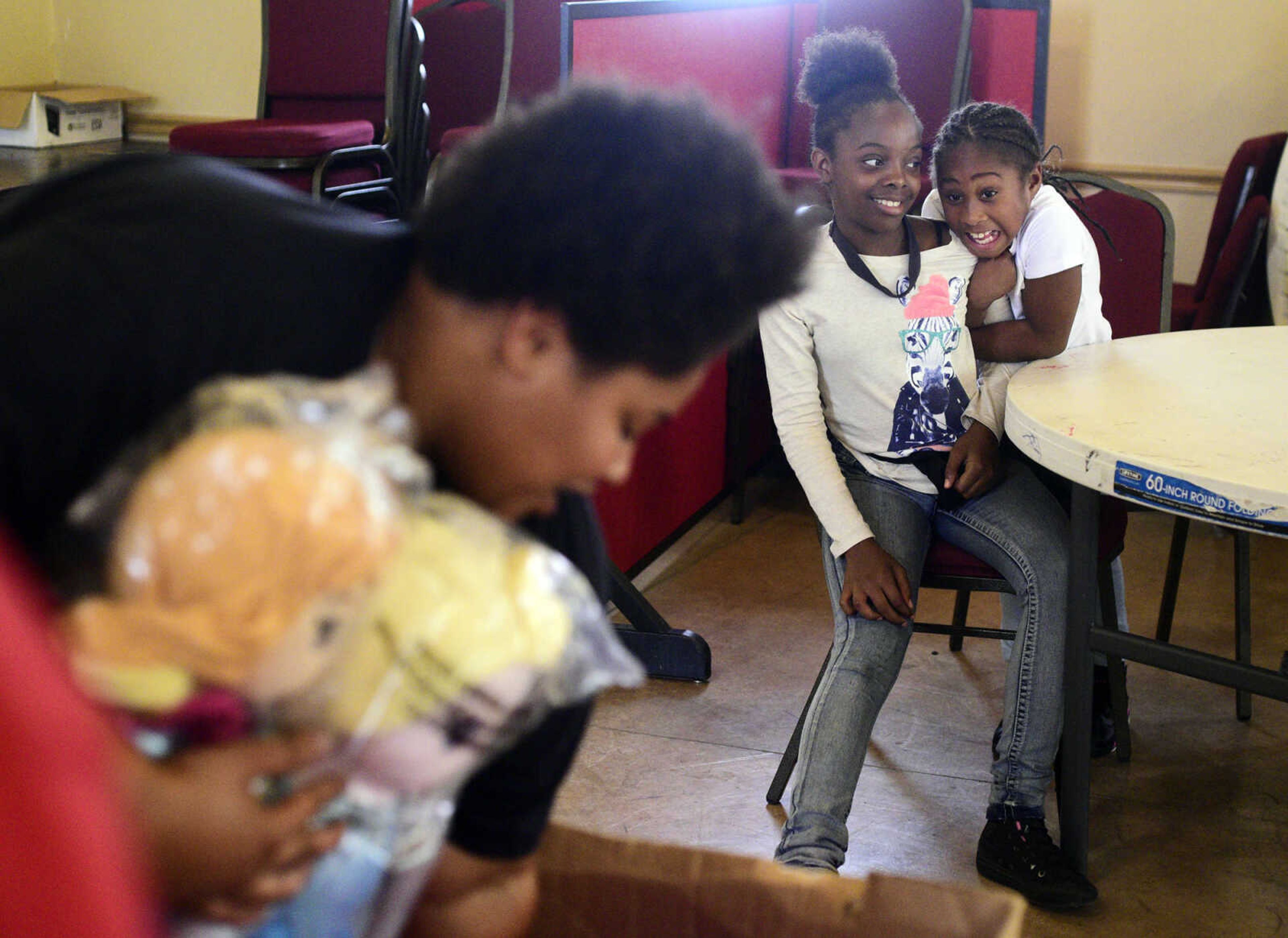 Alexya Jones, right, grabs onto Marshauntis Washington as she sees Cherish Moore pull out toys from a box on Monday, Aug. 14, 2017, during the Salvation Army's after school program at The Bridge Outreach Center in Cape Girardeau.