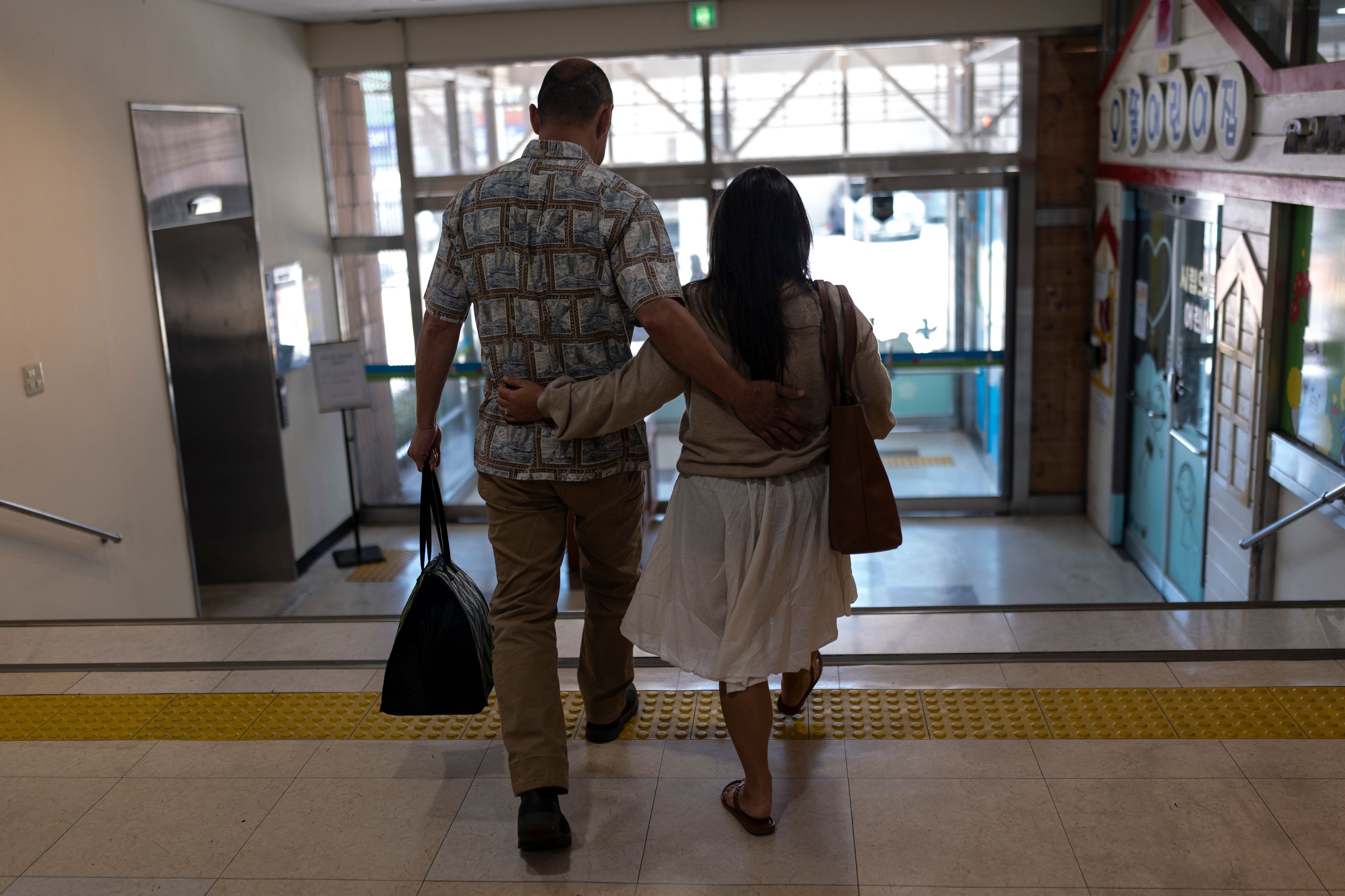 Kenneth Barthel, left, who was abandoned and later adopted to the United States at 6 years old, and his wife, Napela, comfort each other as they leave the Busan Metropolitan City Child Protection Center in Busan, South Korea, Friday, May 17, 2024, after searching for documents that could lead to finding his birth family. (AP Photo/Jae C. Hong)