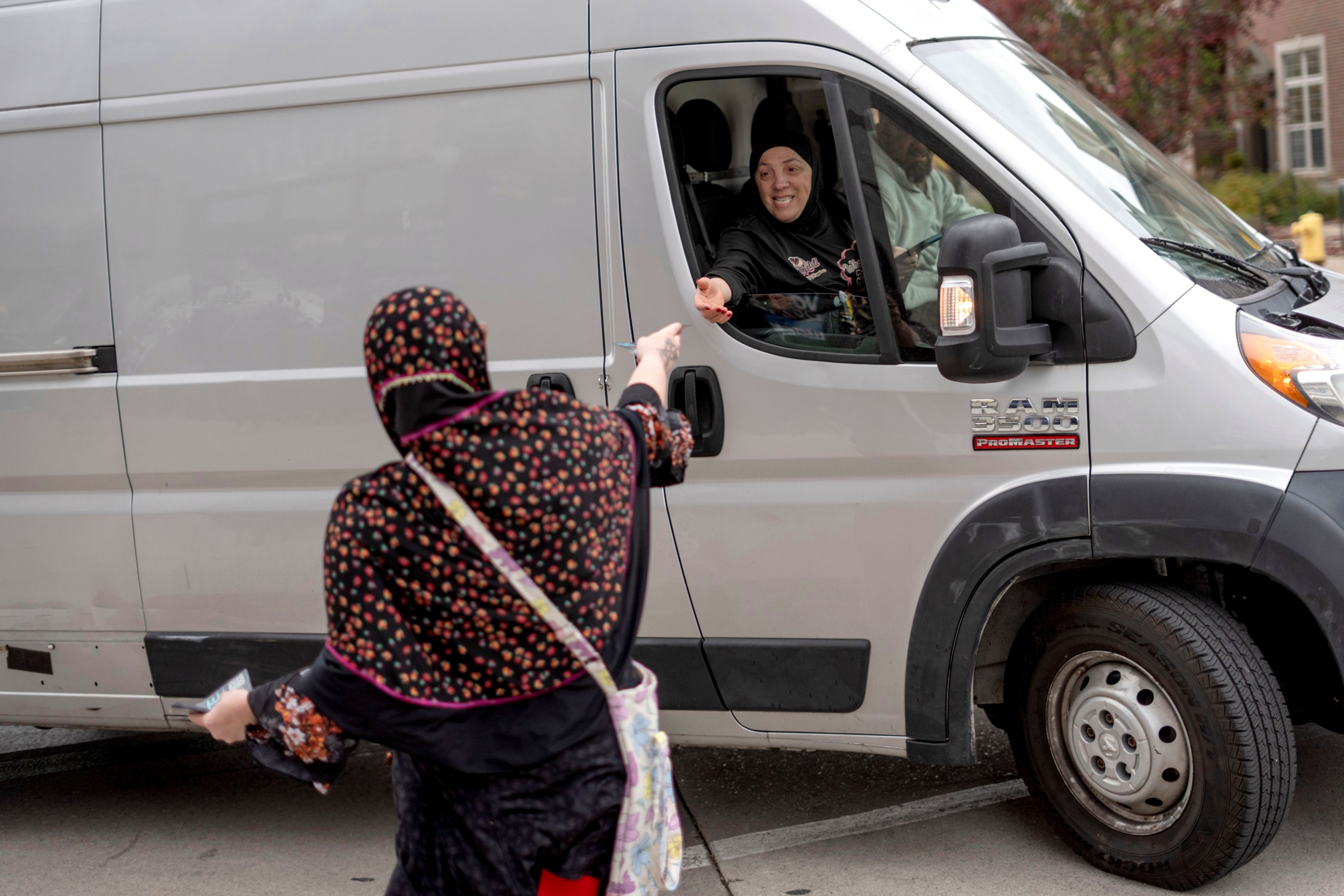 Chelsey Salama, left, with the Abandon Harris movement, hands out a flyer to passing motorists encouraging them to vote for Green Party presidential candidate Jill Stein, Monday, Nov. 4, 2024, in Dearborn, Mich., the nation's largest Arab-majority city. (AP Photo/David Goldman)