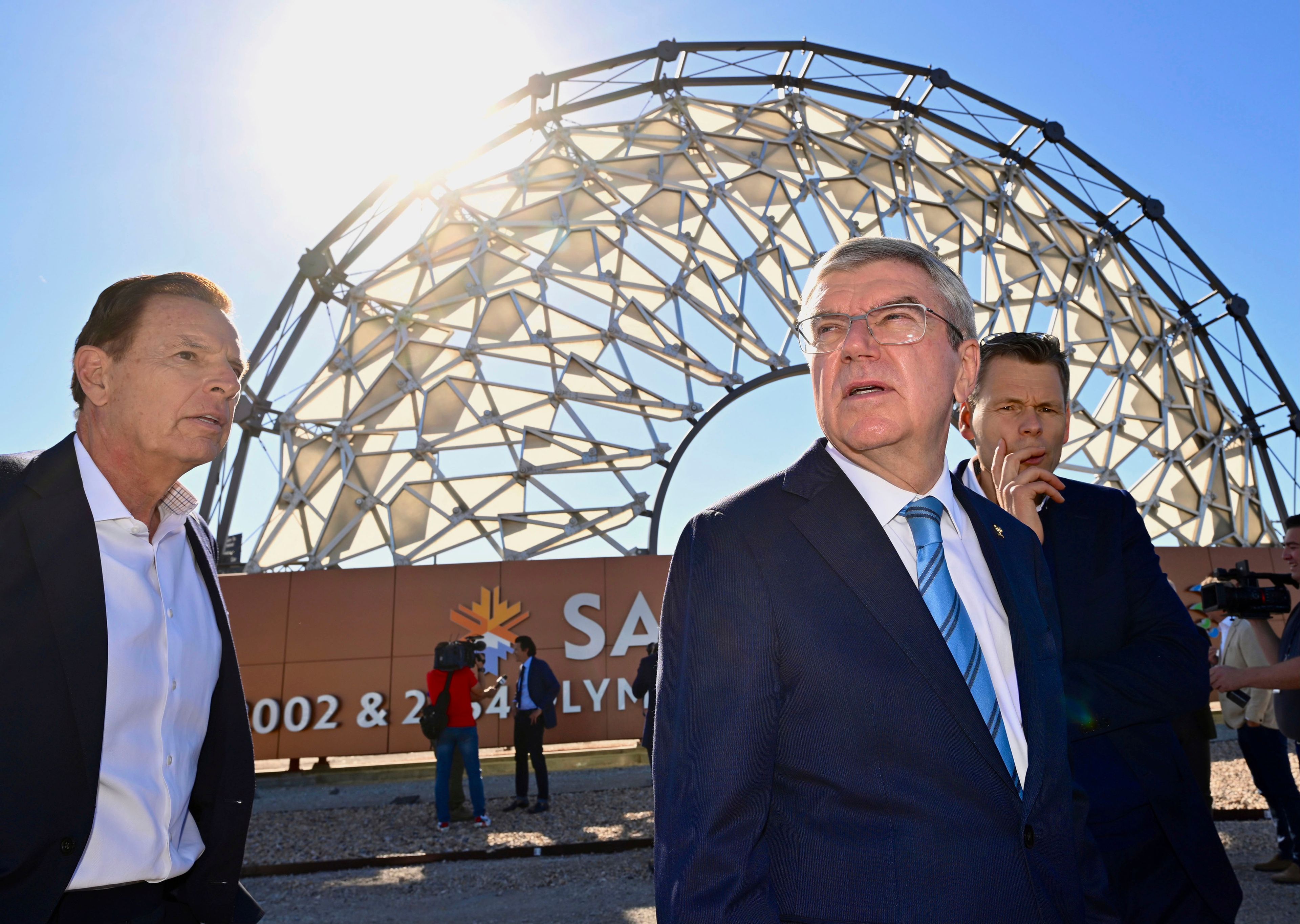 Fraser Bullock, left, the president and CEO of the Salt Lake City-Utah Committee for the Games, joins International Olympic Committee President Thomas Bach, foreground right, near the Hoberman Arch at the Salt Lake City International Airport, as he leads a delegation visiting ahead of the 2034 Winter Olympics, Friday Sept. 27, 2024. (Scott G Winterton/The Deseret News via AP)