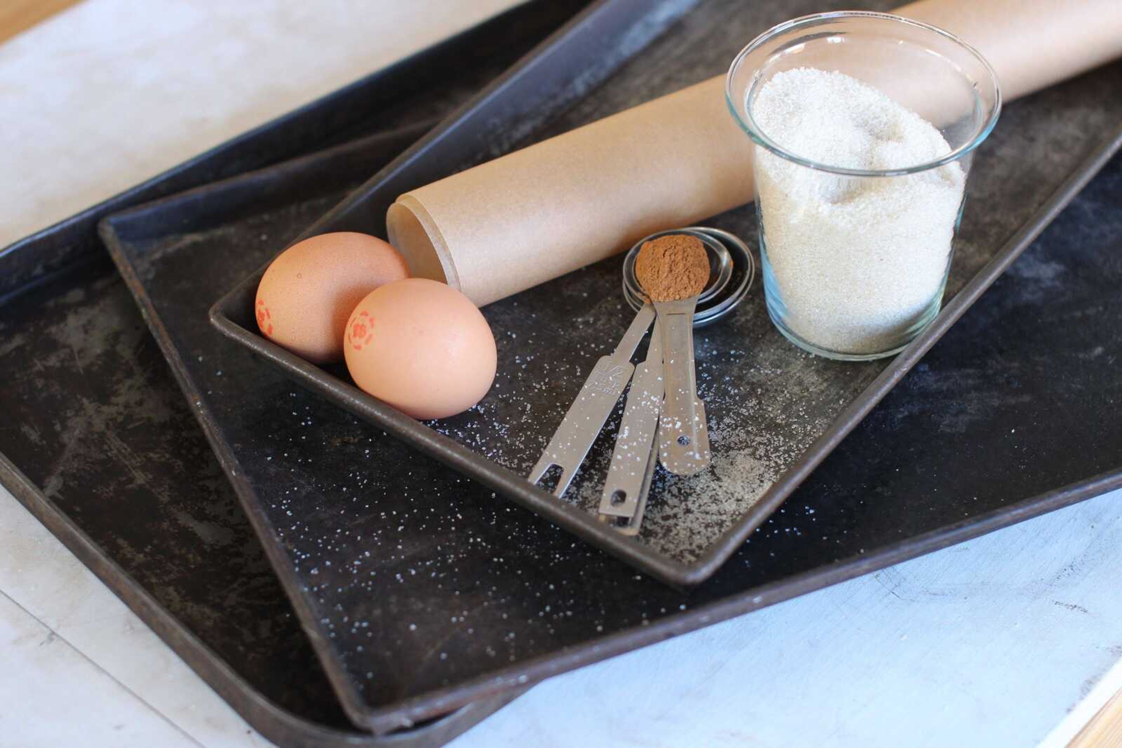 CORRECTS ITEM TO A ROLL OF KITCHEN PARCHMENT, INSTEAD OF A ROLLING PIN -- This photo shows eggs, measuring spoons, a roll of kitchen parchment, baking sheets and a glass of flour. These are some of the items that can help you make cookies like a baking professional. (AP Photo/Matthew Mead)