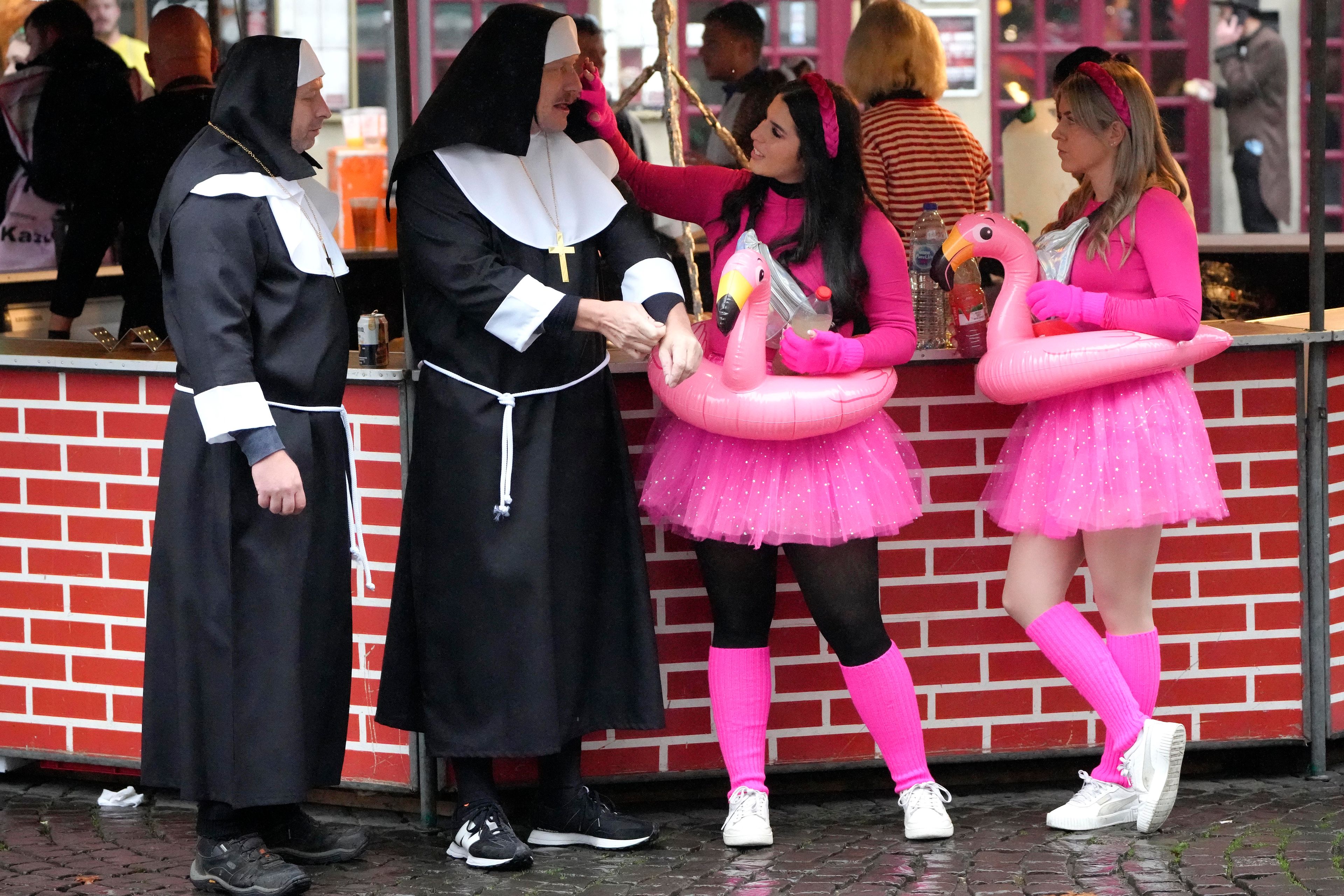 Revelers costumed as nuns and flamingos meet at the central Heumarkt while tens of thousands of carnival fools take to the streets of Cologne, Germany, on Monday, November 11, 2024, heralding the official start of the carnival season. (AP Photo/Martin Meissner)