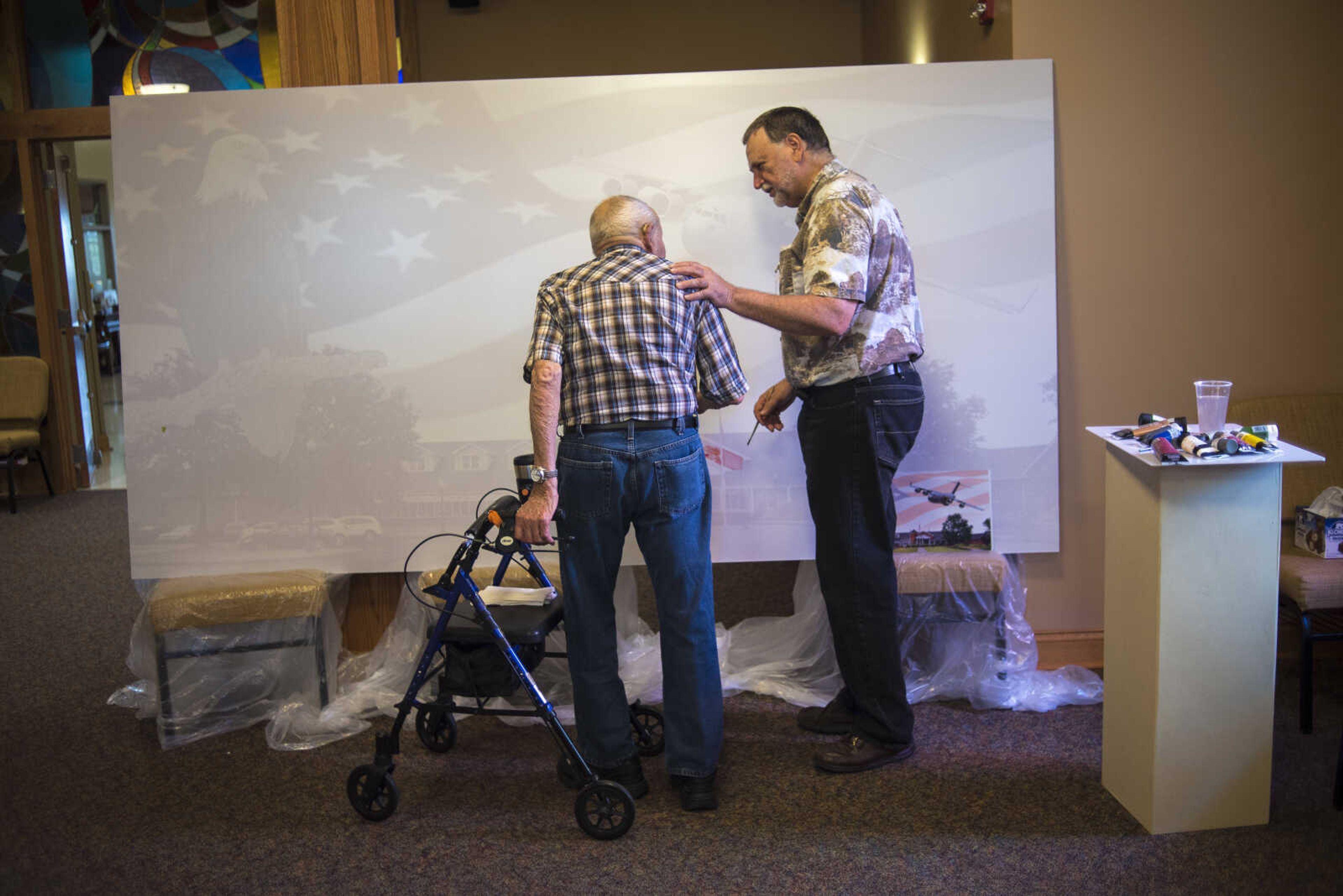 Aaron Horrell, right, places his hand on the shoulder of Alvin Davie, left, after he helped contribute paint for Paint-For-A-Cause where the residents of the Missouri Veterans Home will be given the opportunity to paint first on the big image Friday, July 28, 2017 in Cape Girardeau. Aaron Horrell will then take the painting to the SEMO District Fair where people can also help paint to raise money for the home.